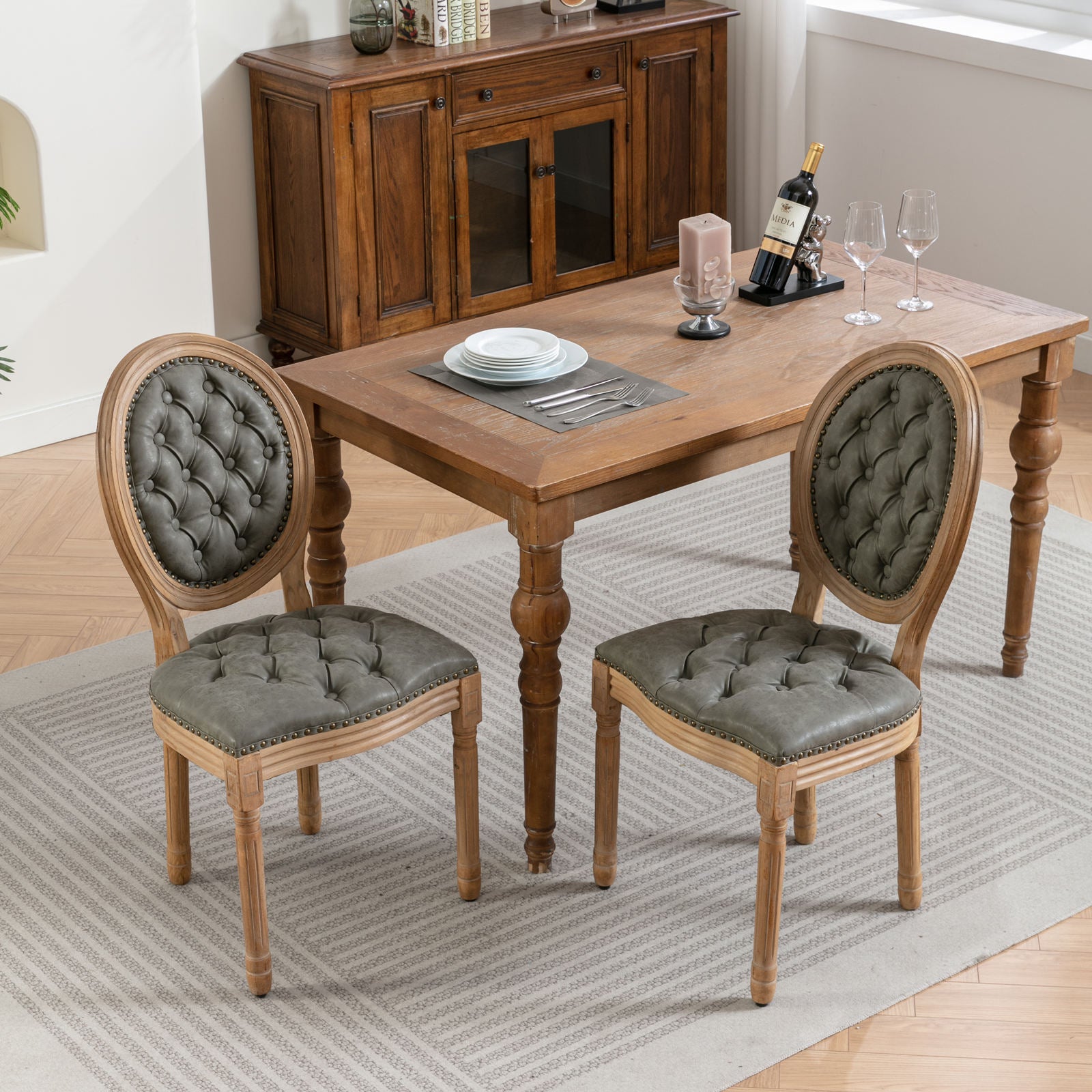 Grey tufted dining chairs with carved wood frames and nailhead trim