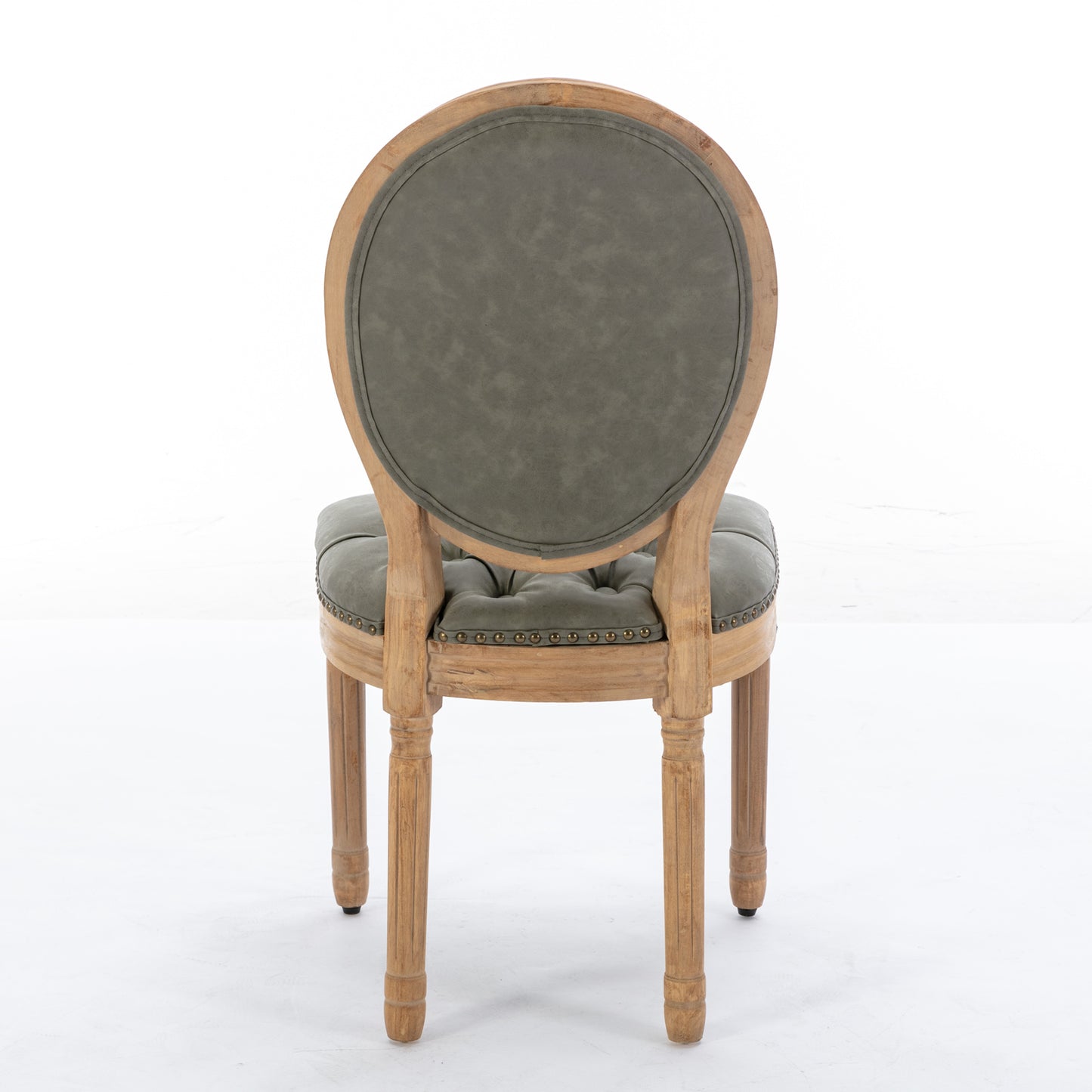 Tufted grey upholstered armchair with distressed wood frame and brass nailhead trim