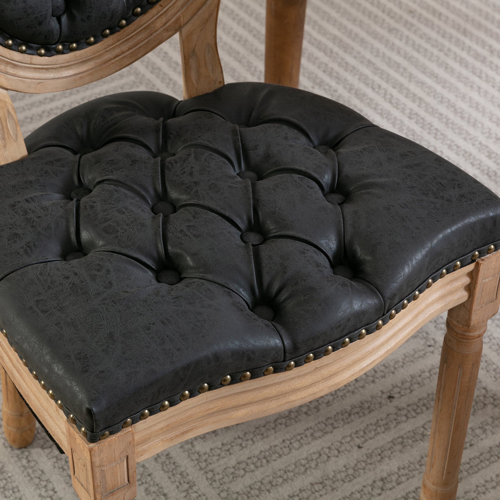 Dark gray tufted faux leather chair seat with brass nailhead trim and wooden frame