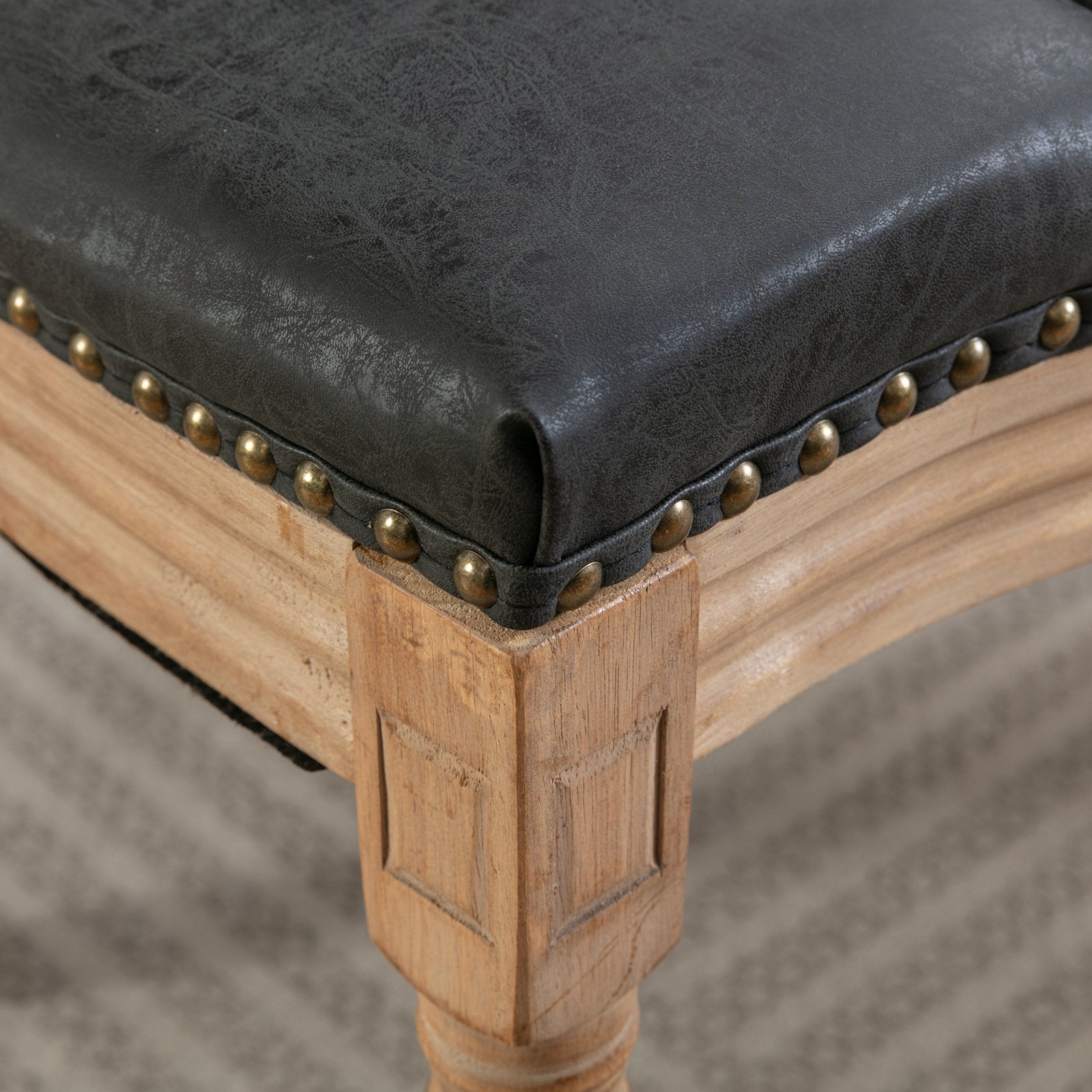 Dark grey faux leather dining chair seat with brass nailhead trim and wooden legs