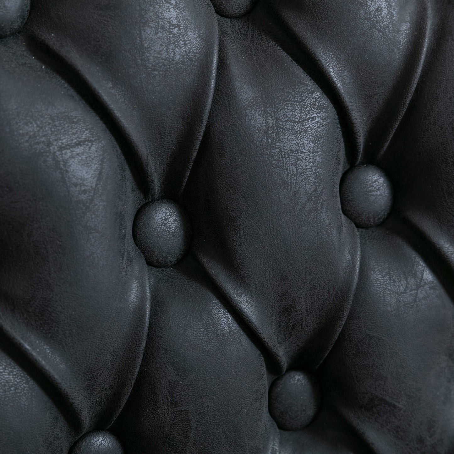 Closeup of black tufted faux leather upholstery detail
