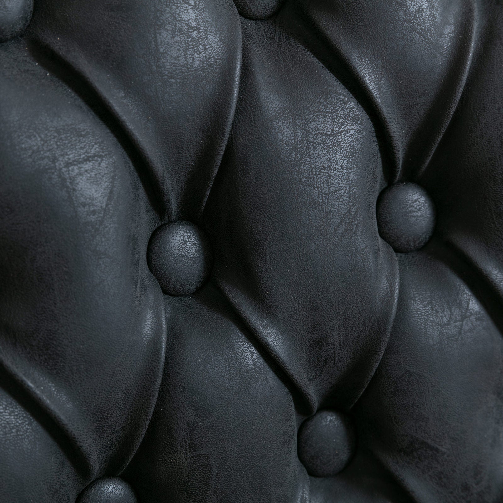 Closeup of black tufted faux leather upholstery detail