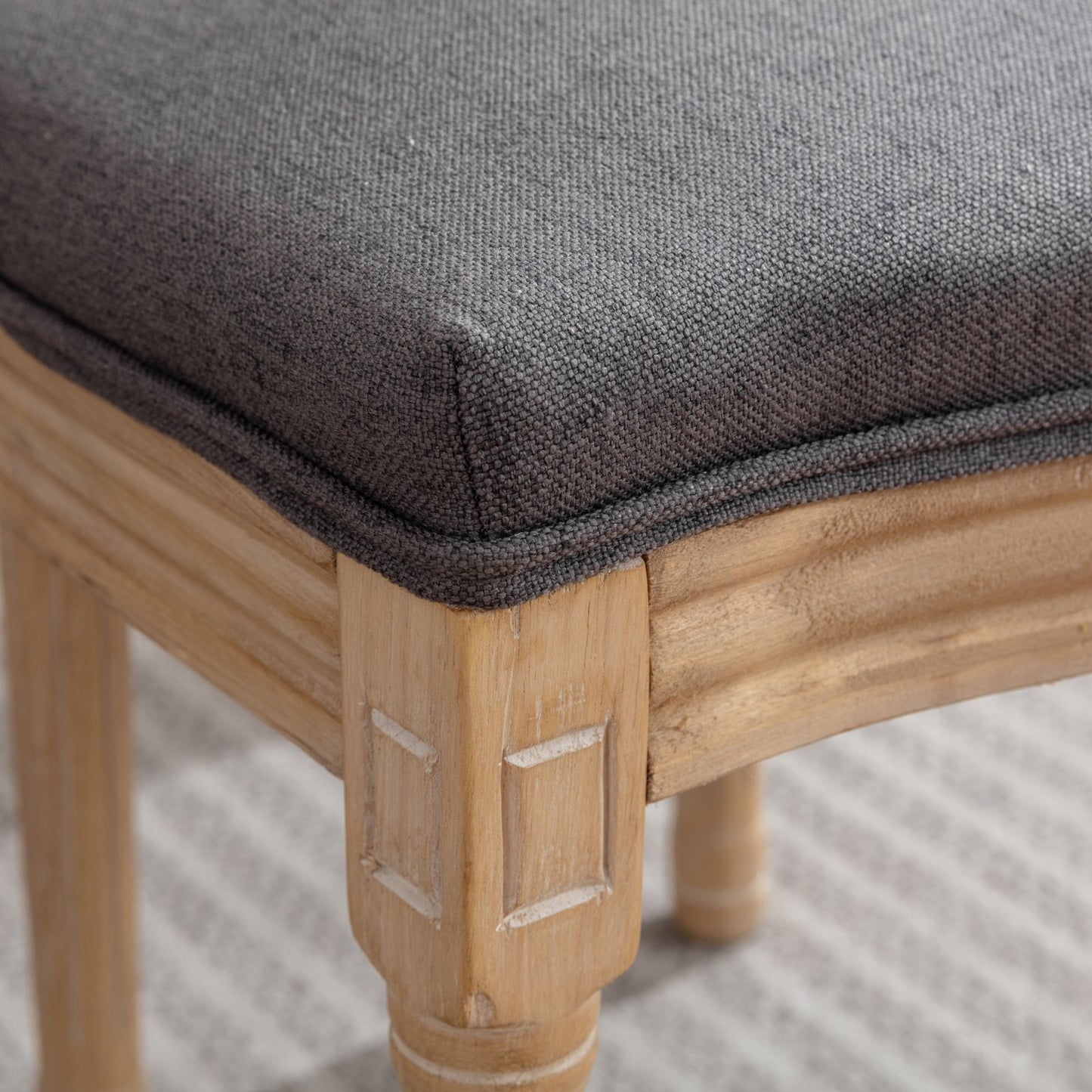 Close up of dark grey upholstered seat cushion on light wood carved chair