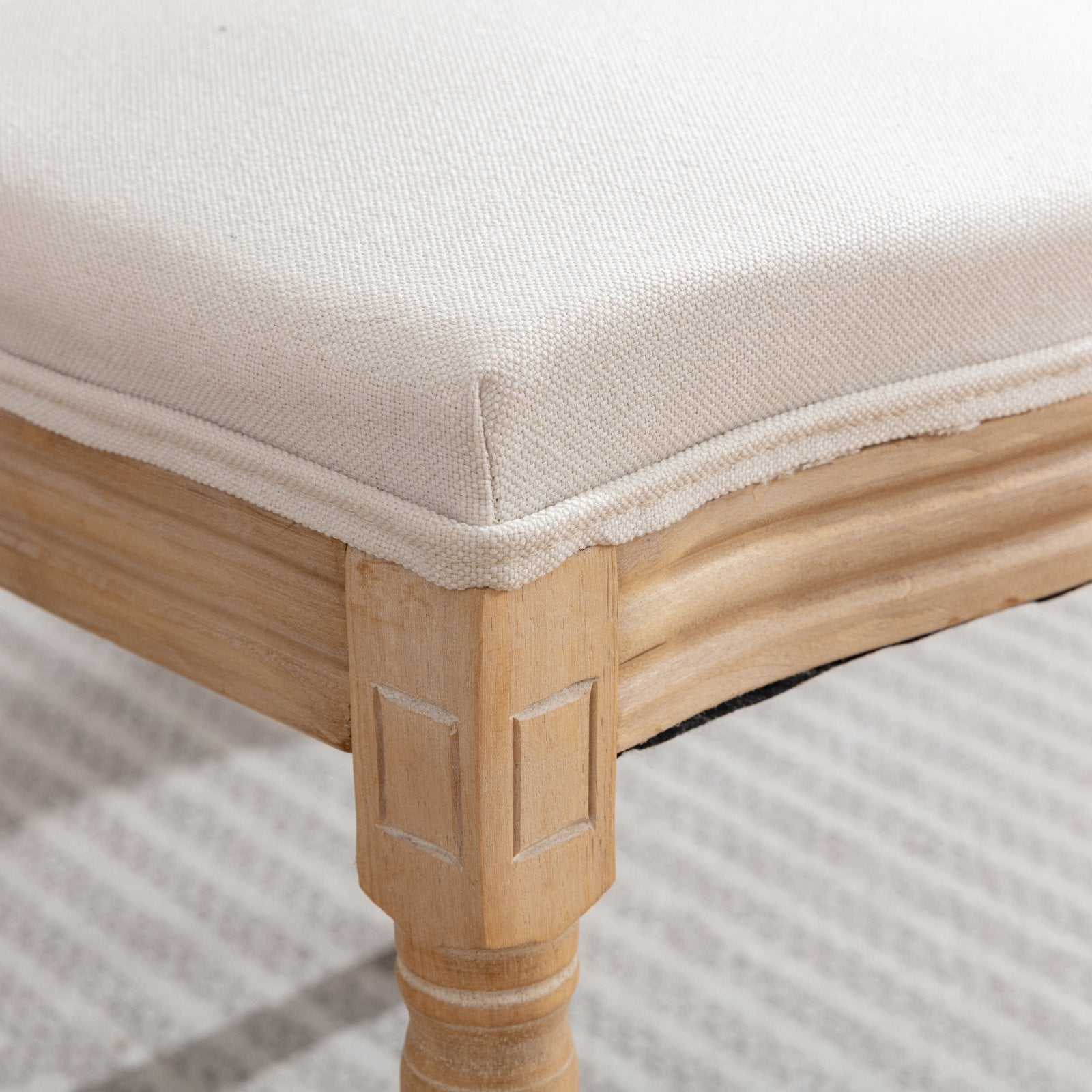 Cream linen upholstered ottoman with carved wooden legs