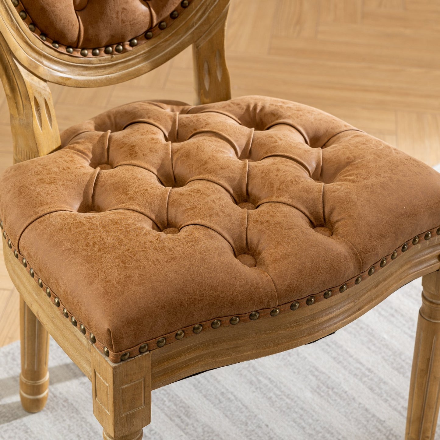 Tufted brown faux leather accent chair with distressed wooden frame and brass nailhead trim