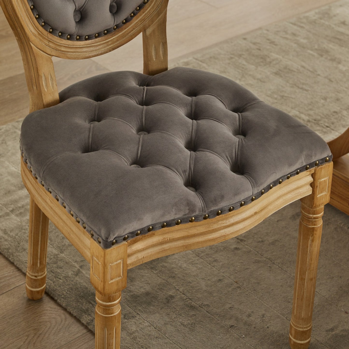 Grey velvet tufted dining chair with ornate wooden legs