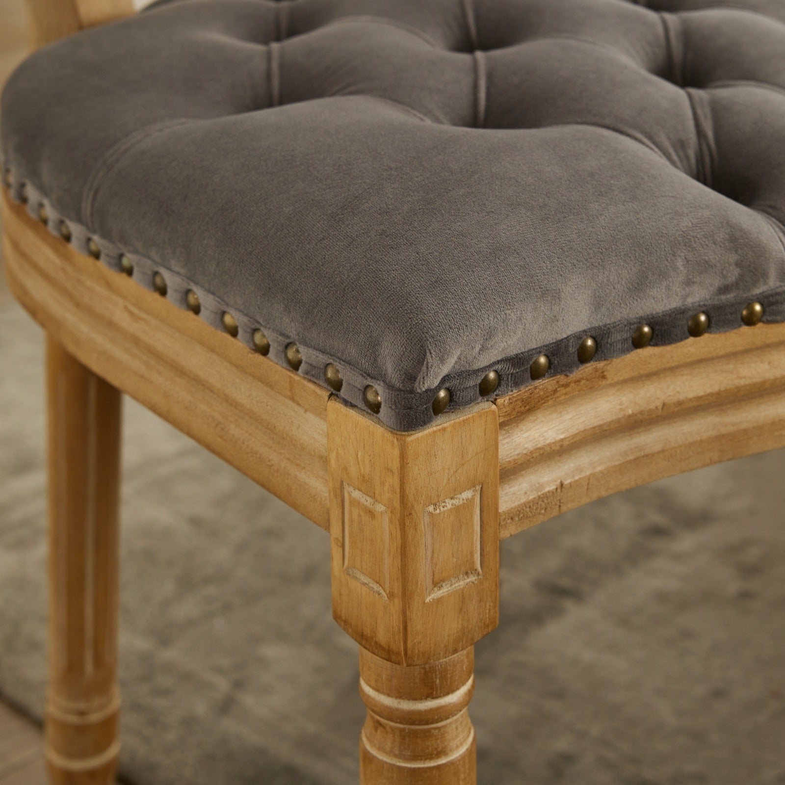 Grey velvet tufted accent chair with antique brass nailhead trim and carved wood legs