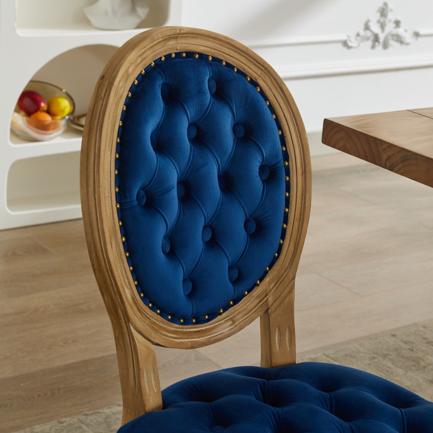 Tufted navy velvet dining chair with distressed wood frame and brass nailhead trim