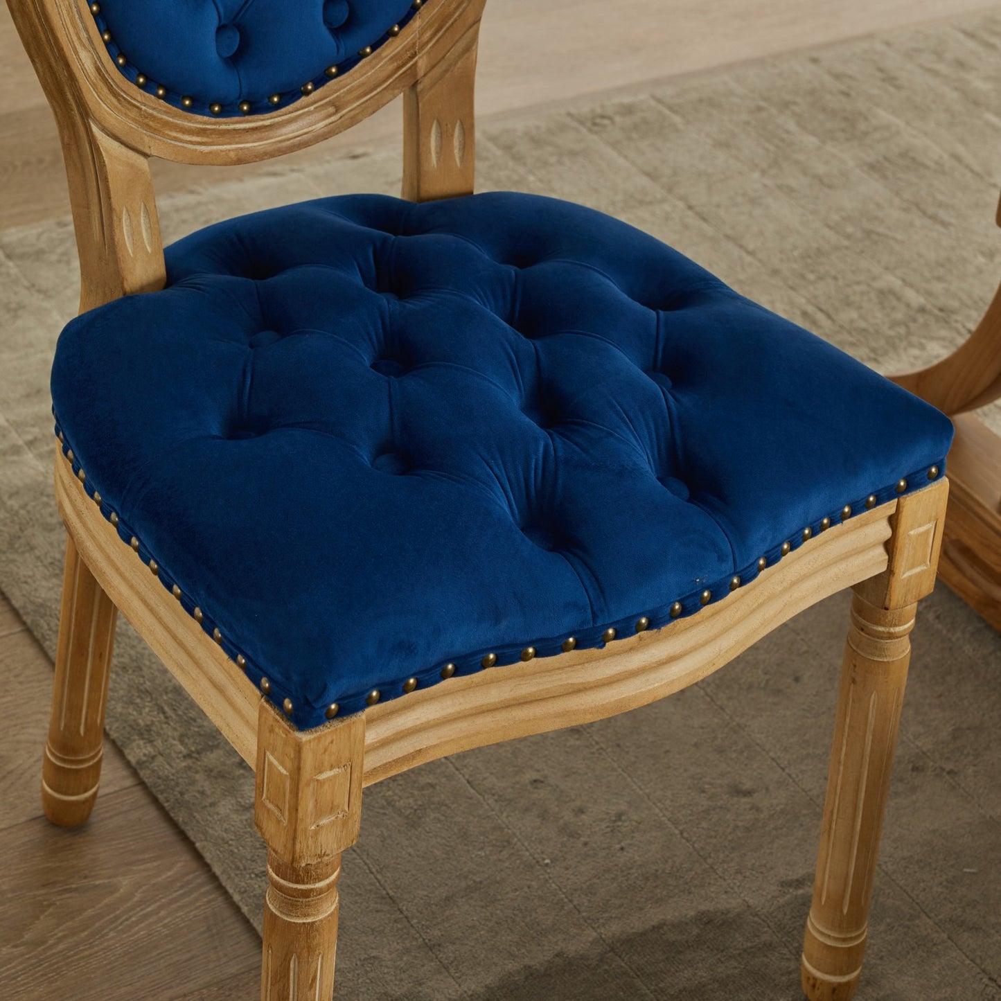 Deep blue velvet dining chair with tufted seat and brass nailhead trim