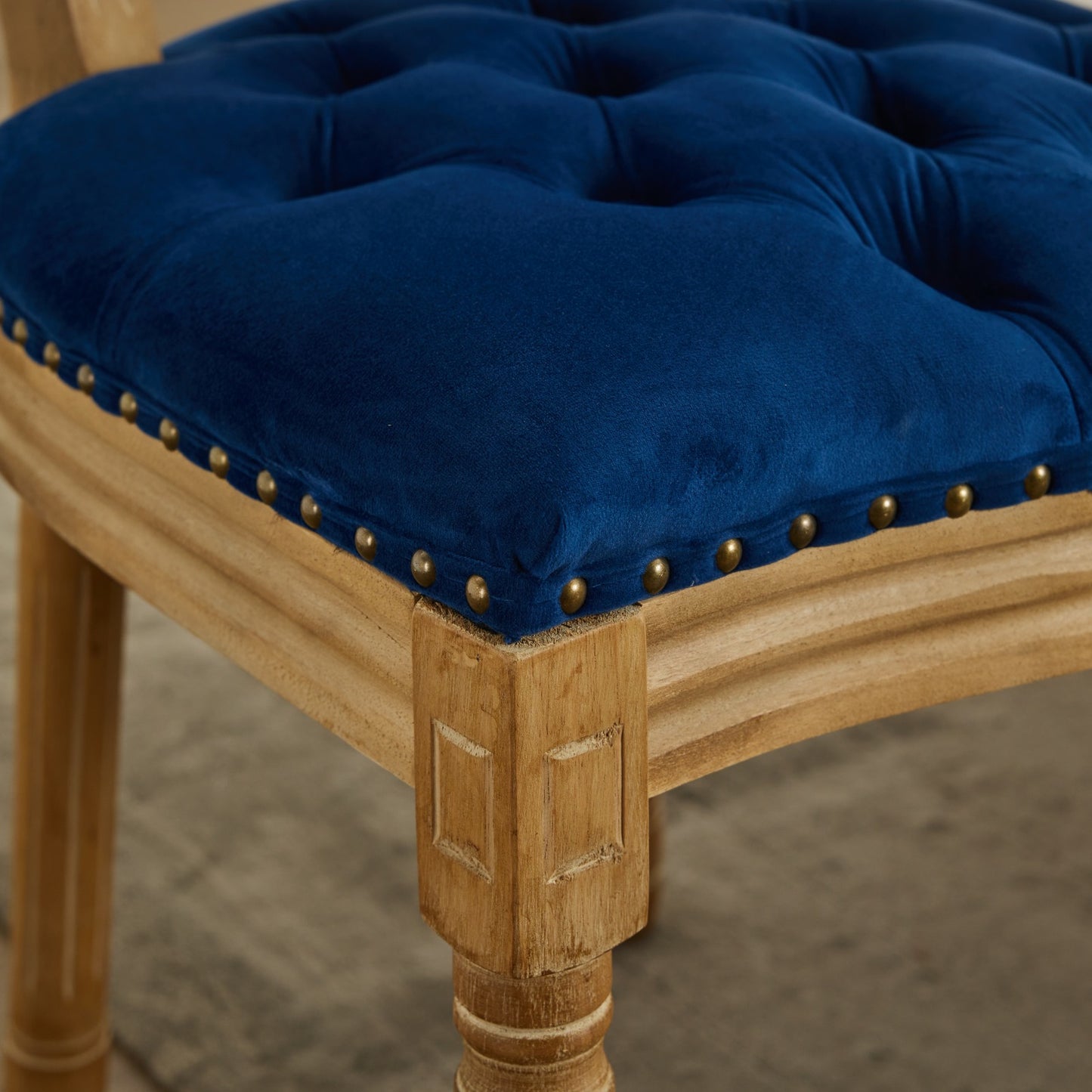 Deep blue velvet tufted accent chair with nailhead trim and distressed wood frame