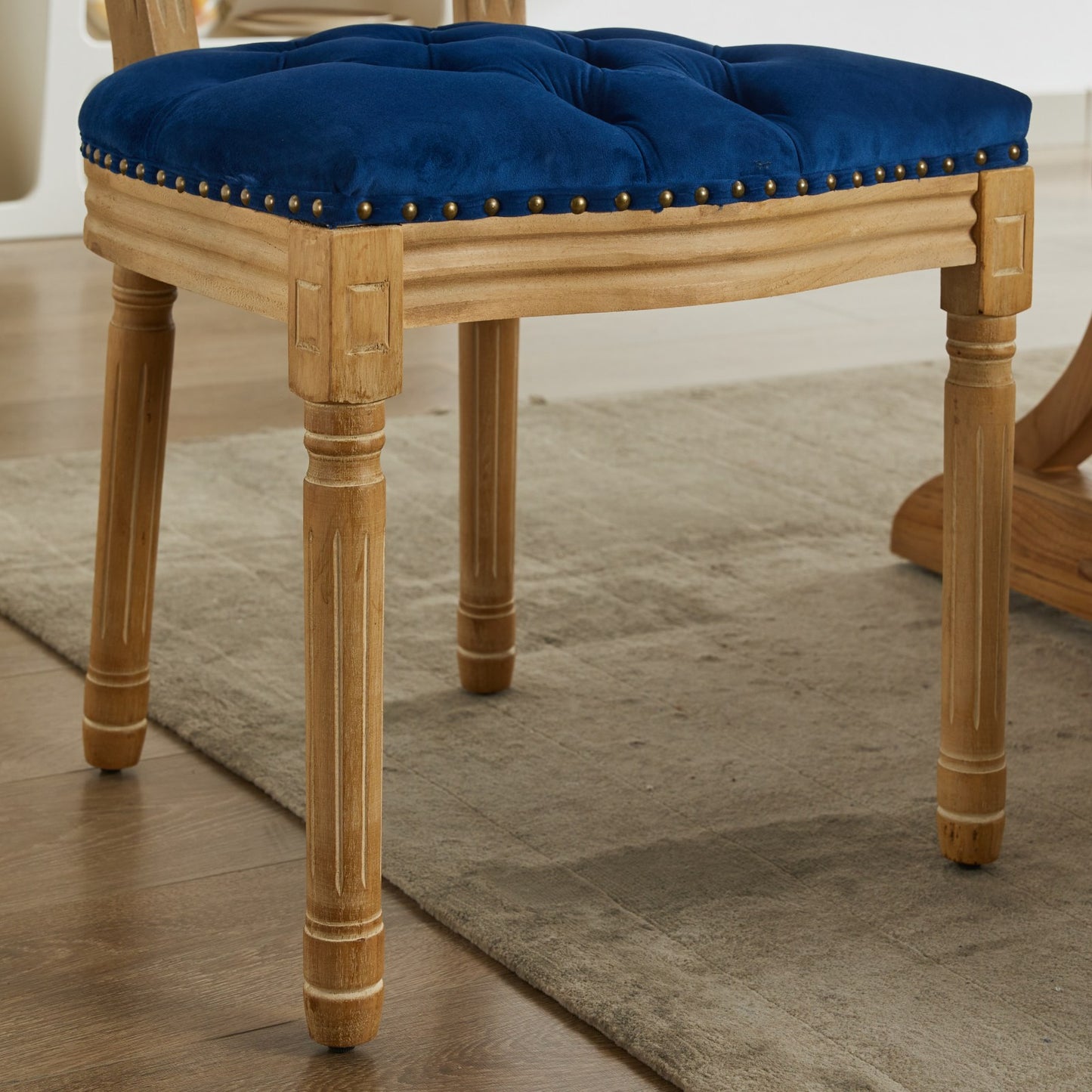 Deep blue velvet tufted chair seat with brass nailhead trim and wooden legs