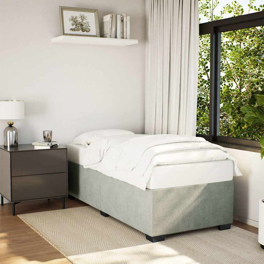 Single bed with grey textured base and white linen bedside table with lamp and books