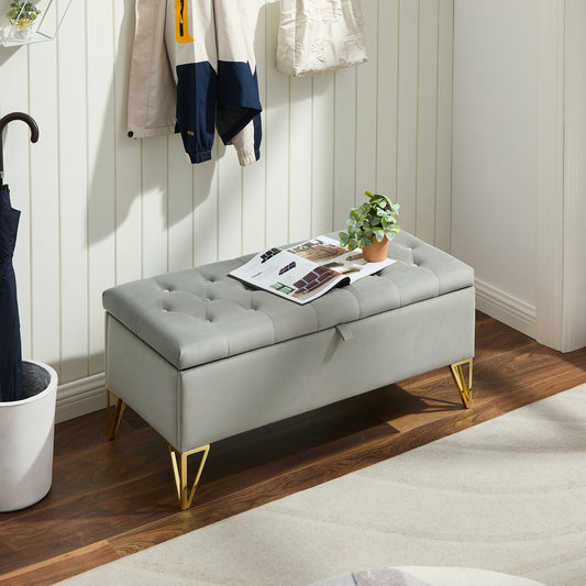 Grey velvet storage ottoman with tufted top and gold legs