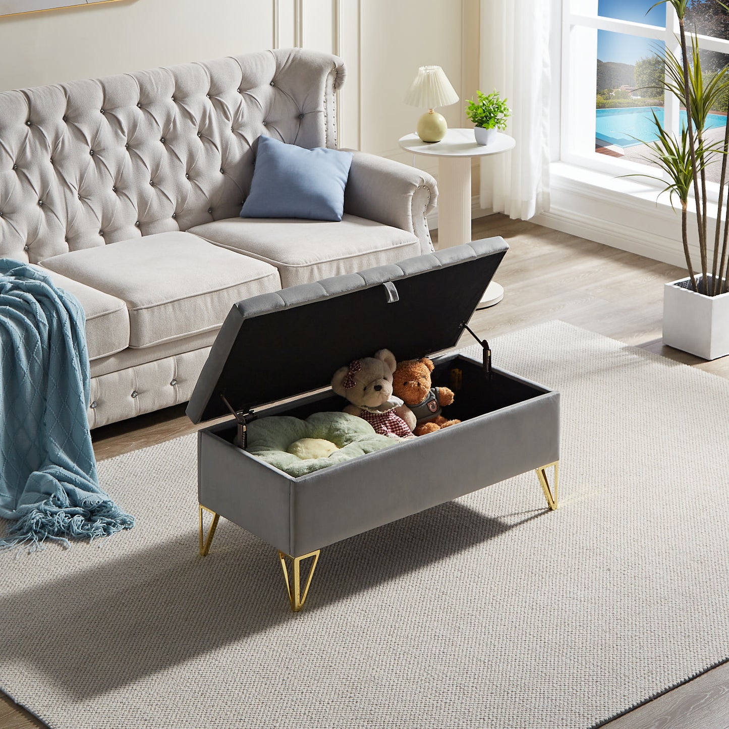 Grey velvet storage ottoman with gold legs and open lid