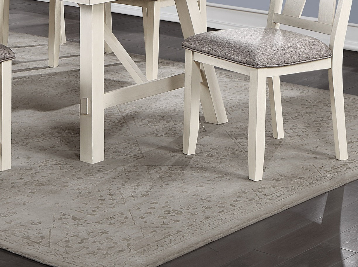 Closeup of a light grey area rug with subtle damask pattern under a dining set