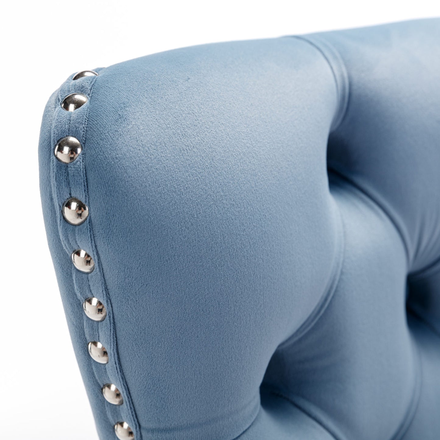 Closeup of blue velvet armchair with silver stud detailing