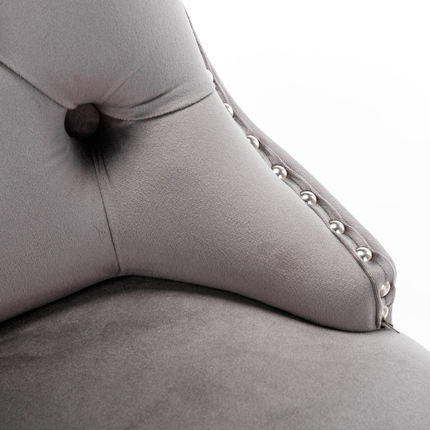 Closeup of plush grey velvet sofa armrest with tufted detailing and silver nailhead trim