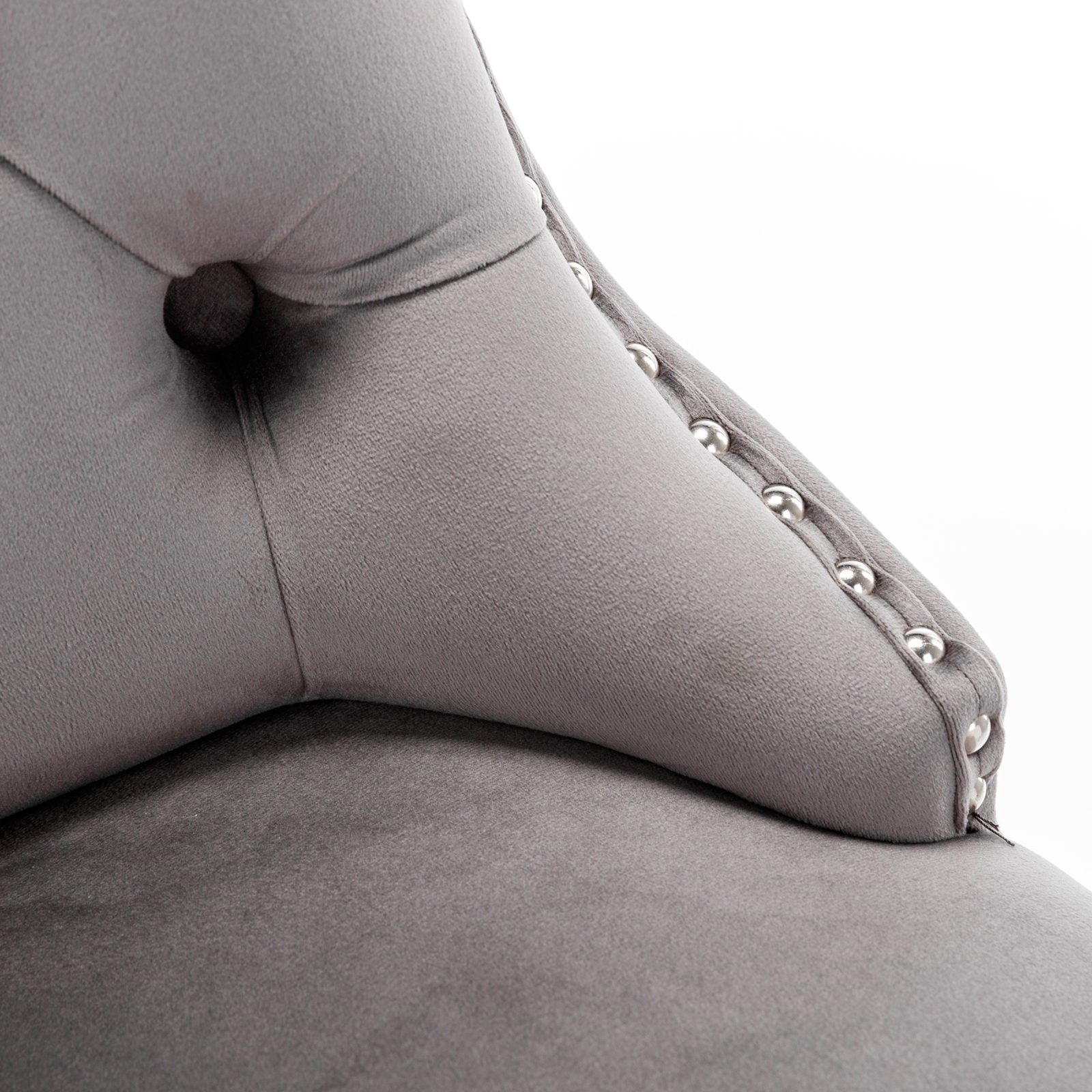 Closeup of plush grey velvet sofa armrest with tufted detailing and silver nailhead trim