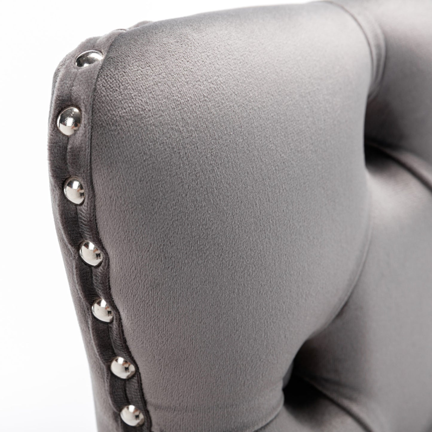 Closeup of a grey velvet armchair cushion with silver nailhead trim