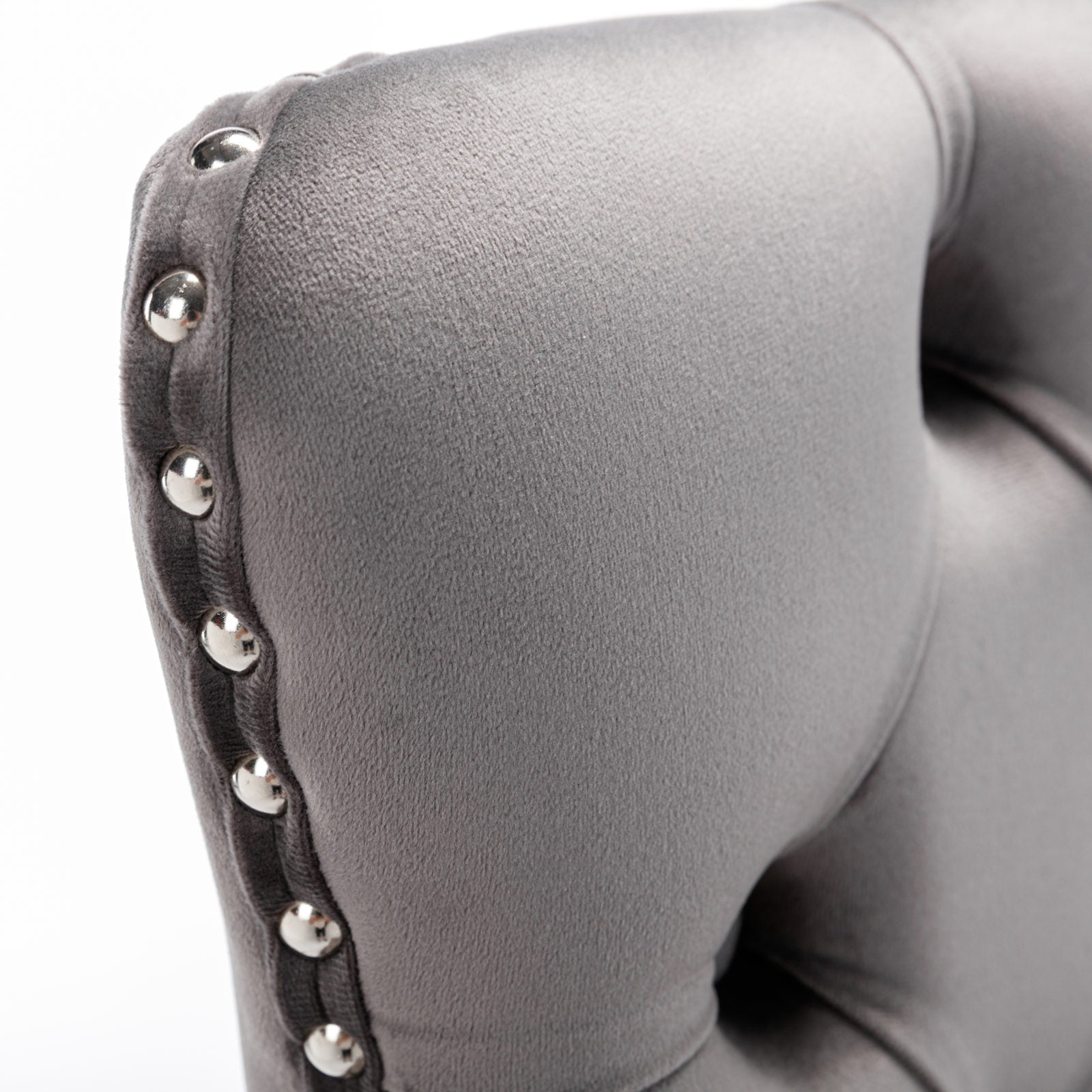 Closeup of a grey velvet armchair cushion with silver nailhead trim