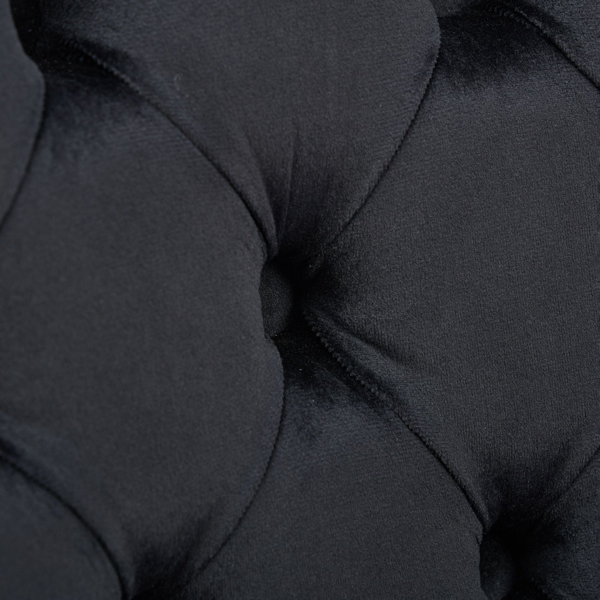 Closeup of black velvet fabric with button tufting detail