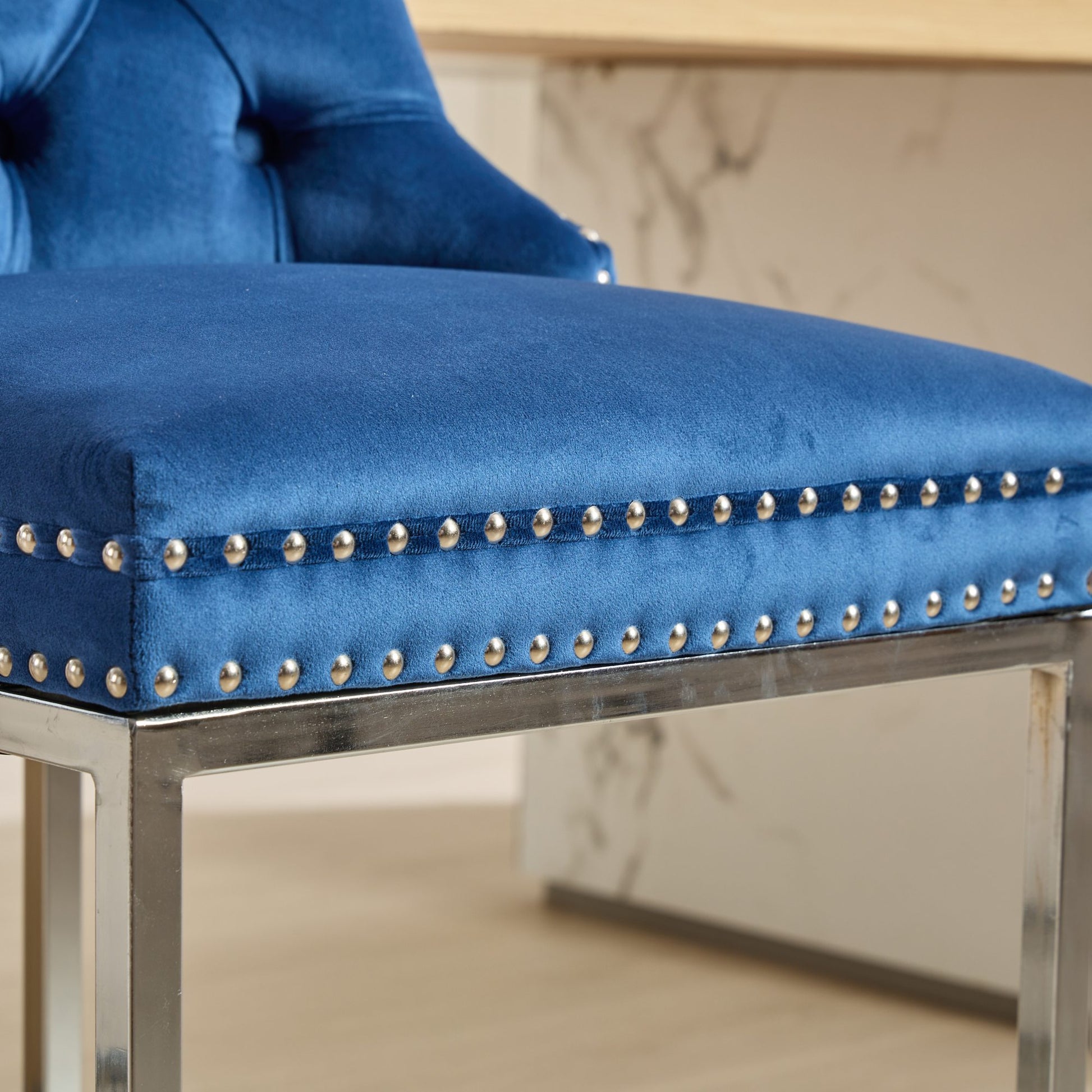 Closeup of royal blue velvet tufted chair seat with silver nailhead trim
