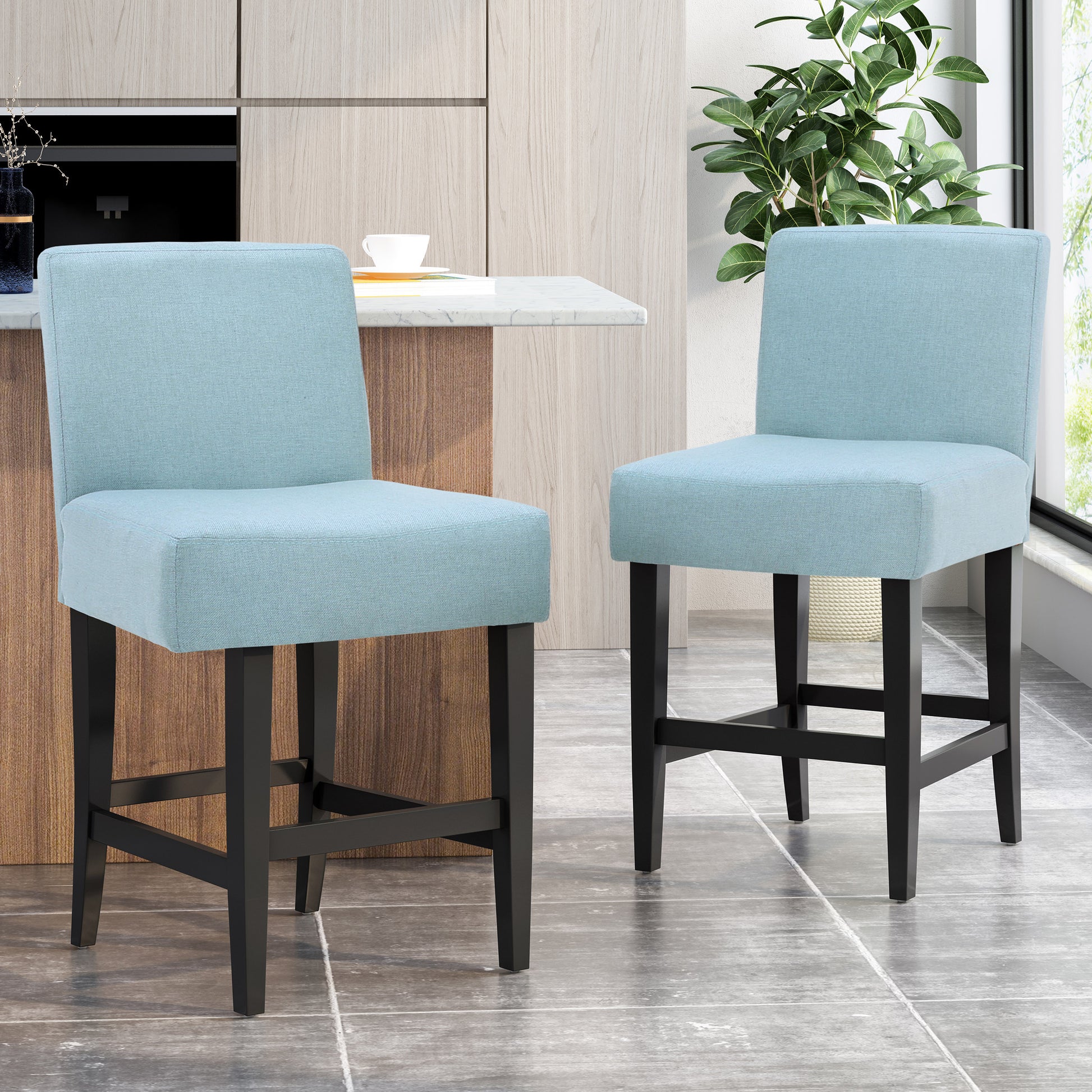 Two light blue upholstered bar stools with black wooden legs in a modern kitchen