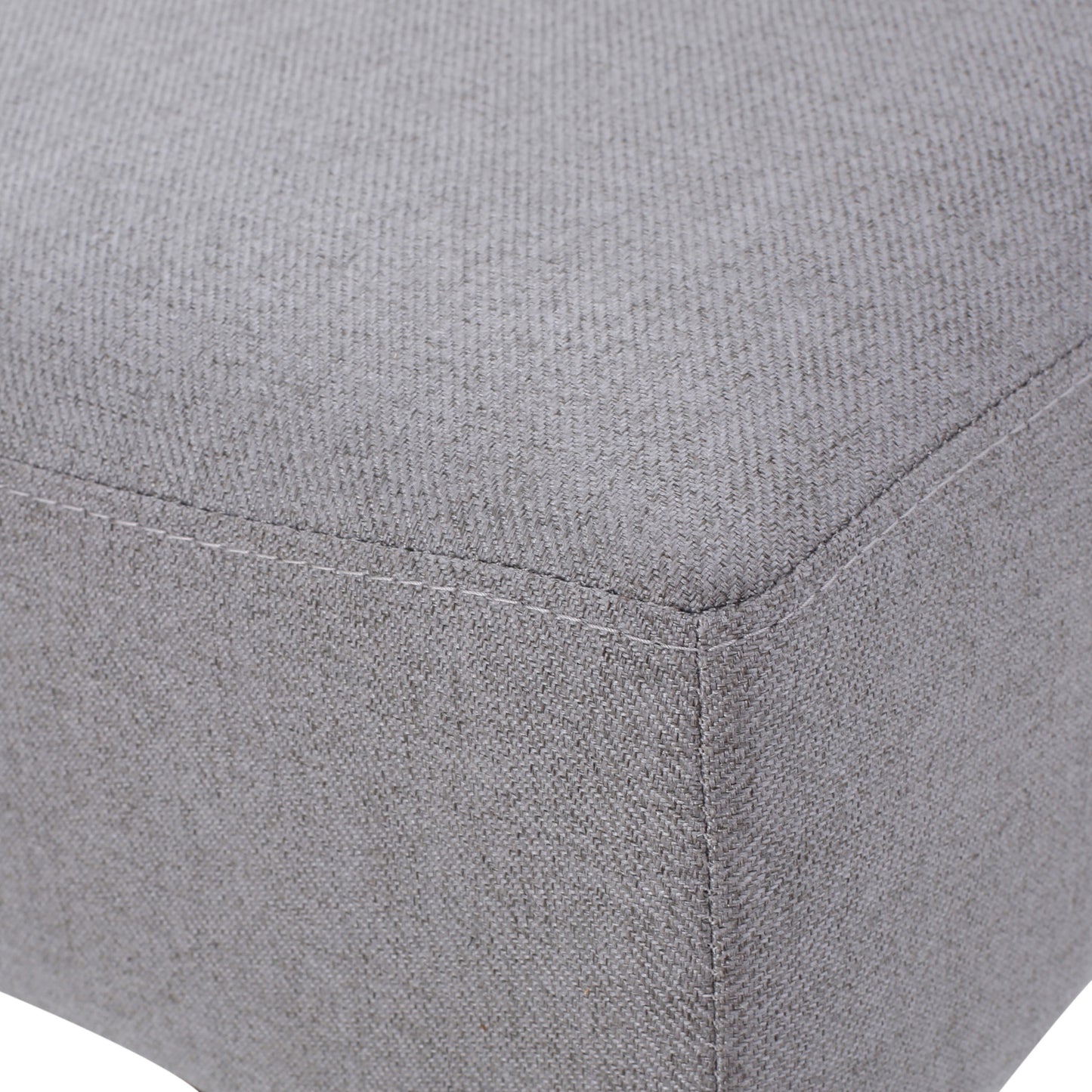 Textured grey linen fabric on a square ottoman corner with visible stitching