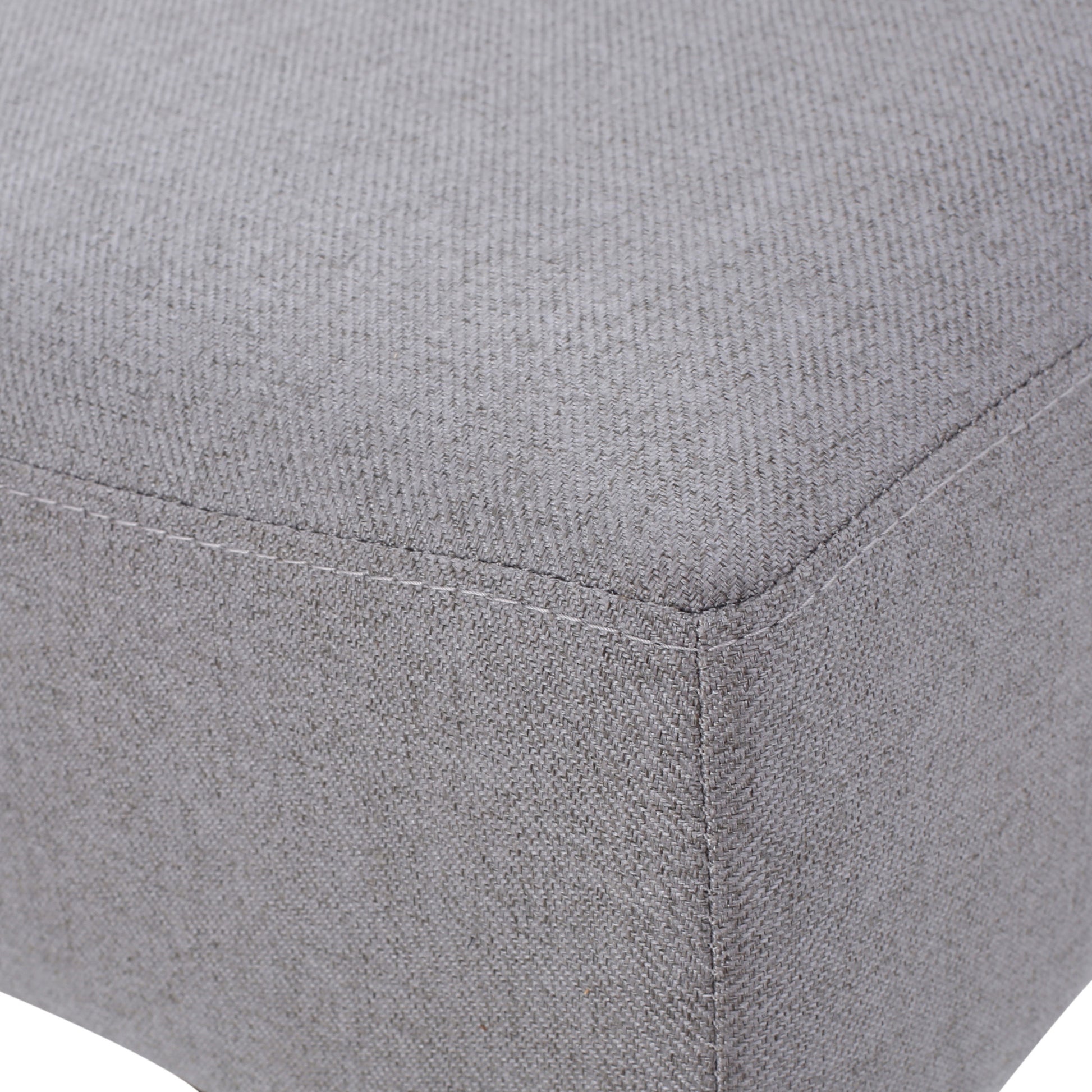 Textured grey linen fabric on a square ottoman corner with visible stitching