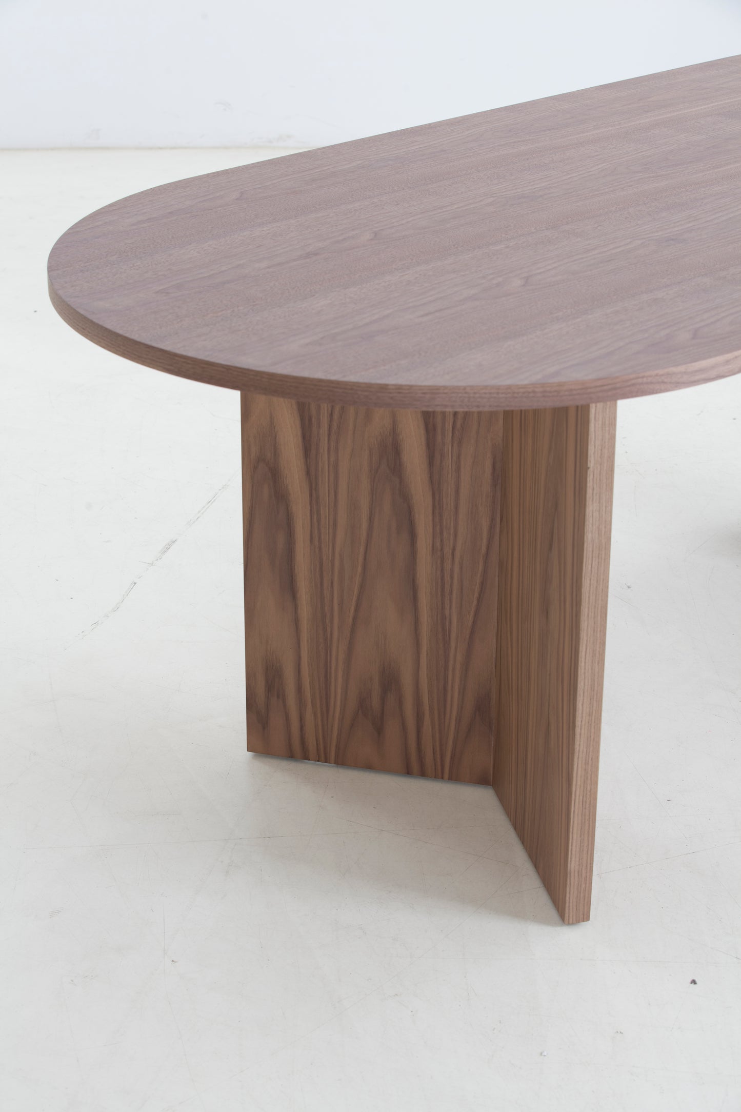 Curved walnut wood dining table with modern pedestal base