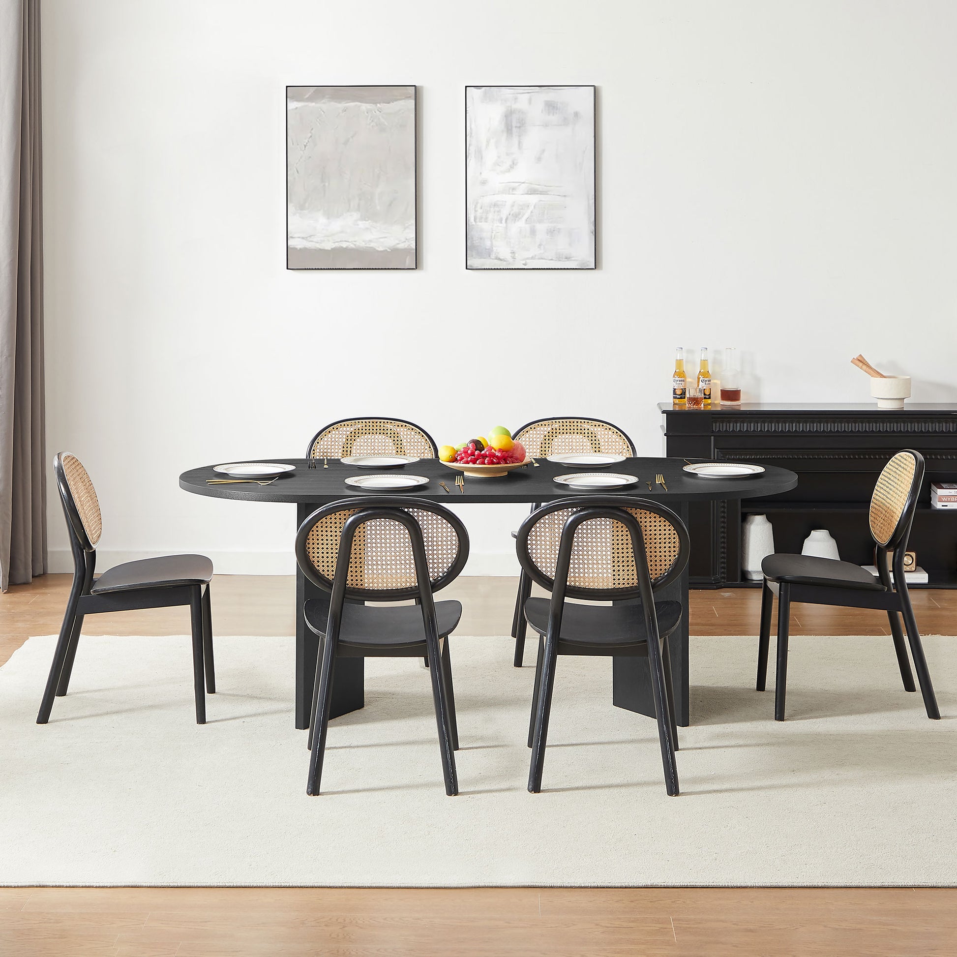 Black oval dining table with caneback chairs and place settings
