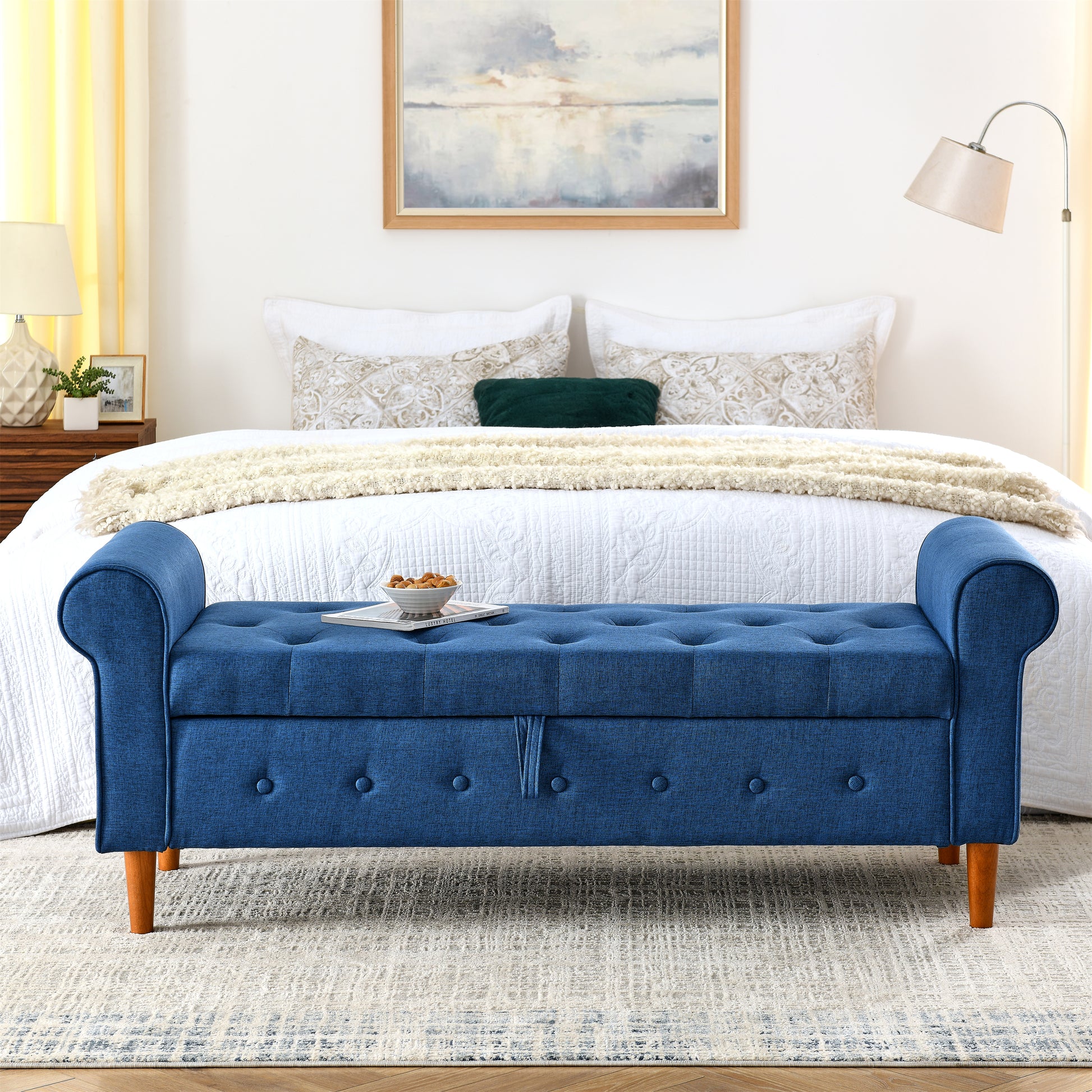 Tufted navy blue storage bench with rolled arms and wooden legs in a bedroom setting