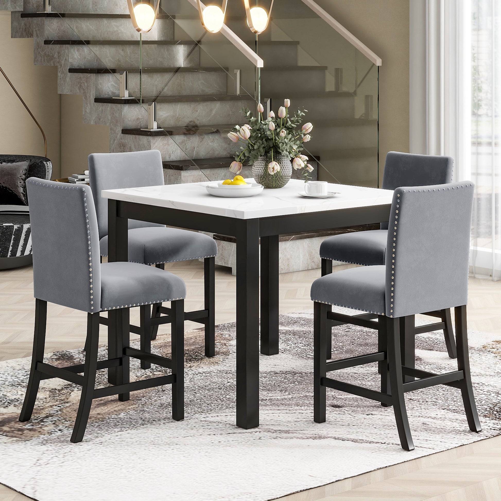 Marble top counter height dining set with gray upholstered stools and nailhead trim