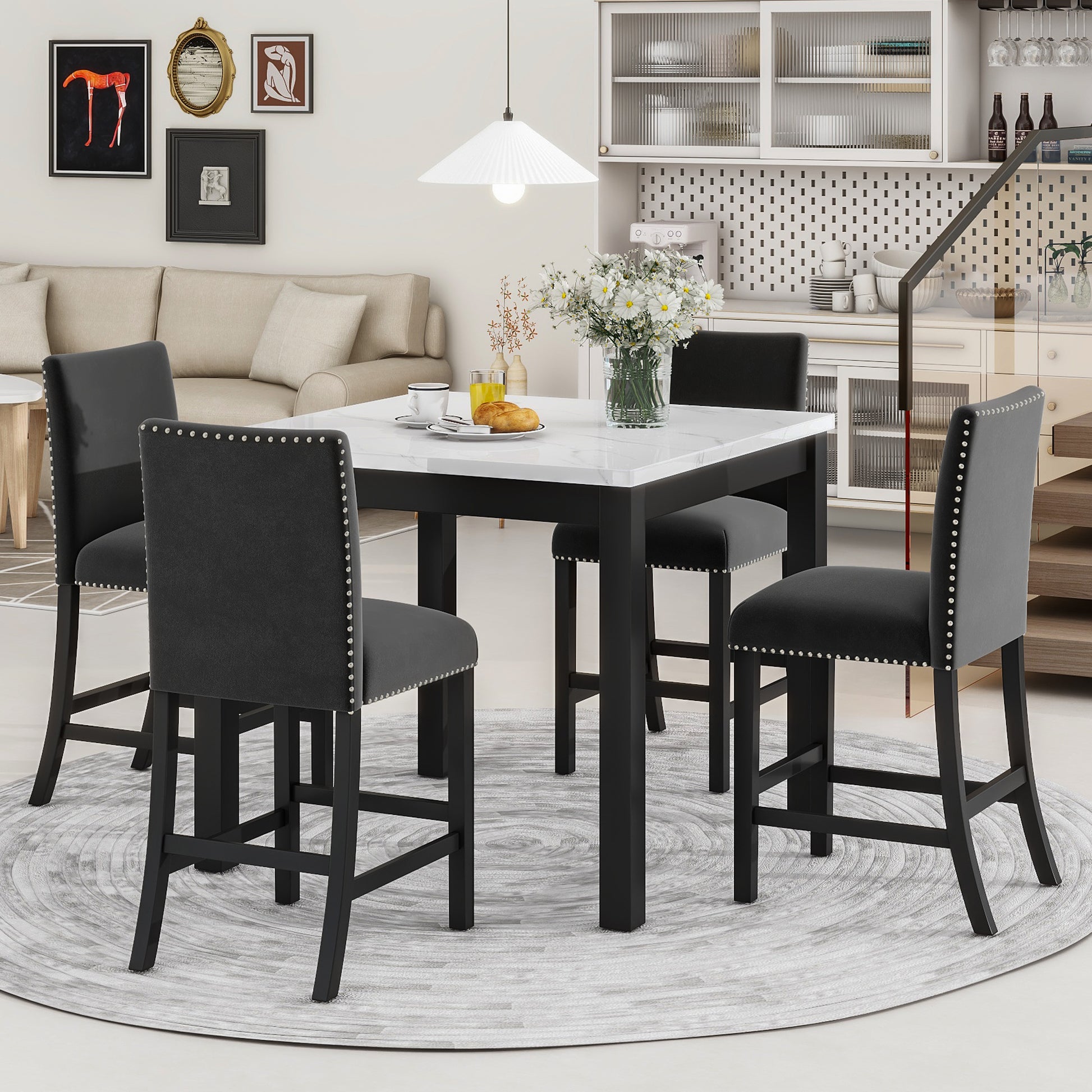 Four black velvet counter height stools with silver nailhead trim around a white marble top dining table
