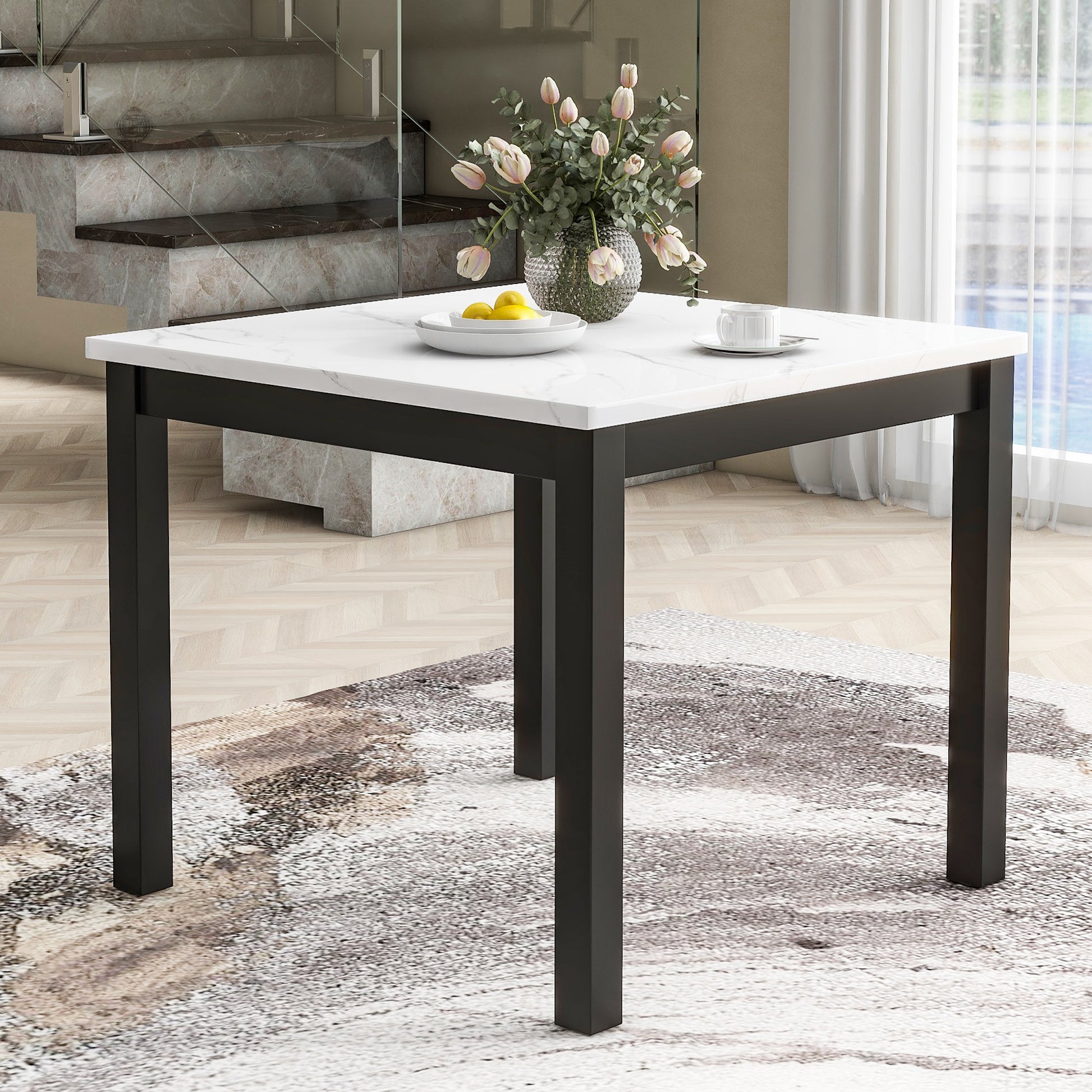 Square marblelook dining table with black metal legs featuring a vase of tulips