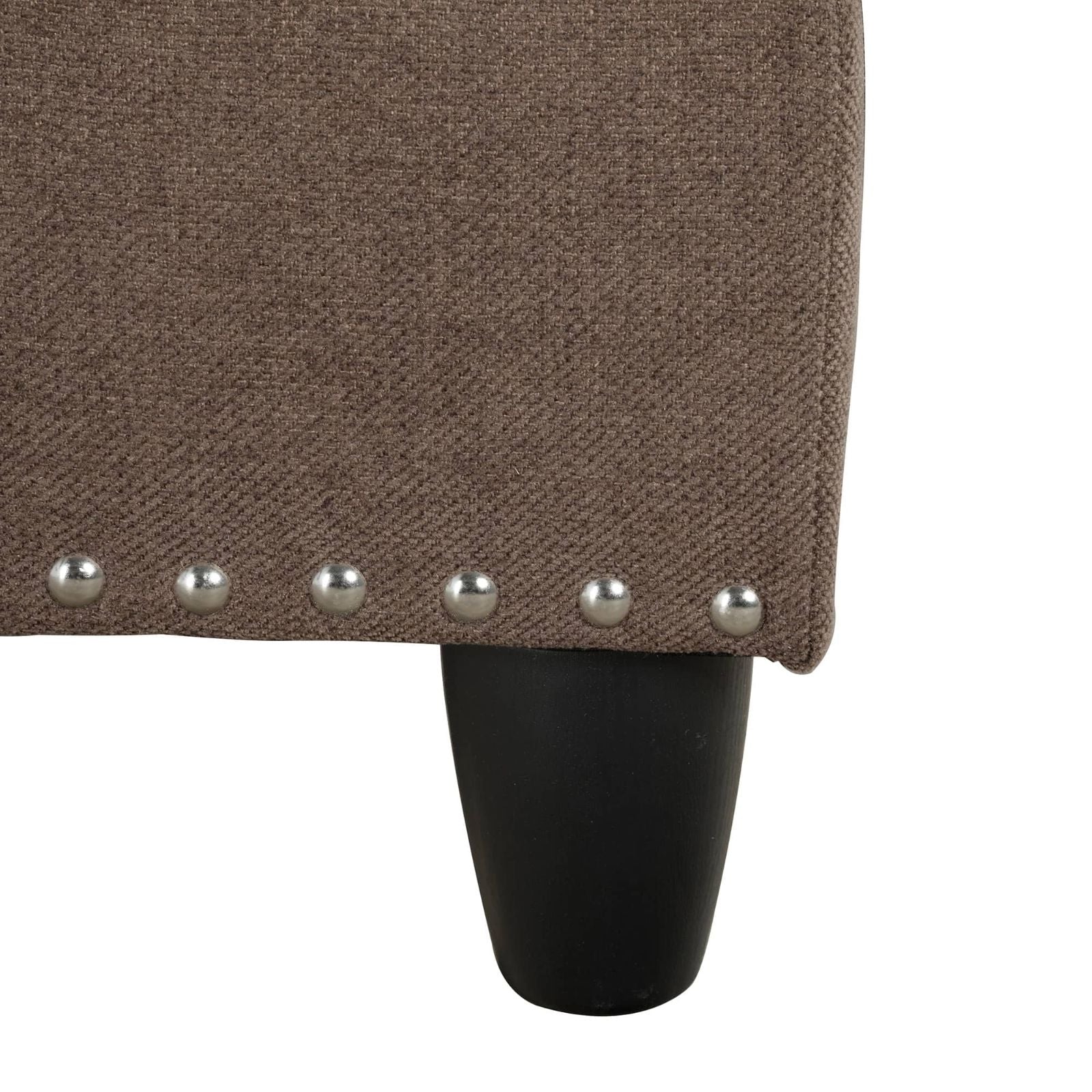 Closeup of brown textured fabric with nailhead trim and a black tapered leg