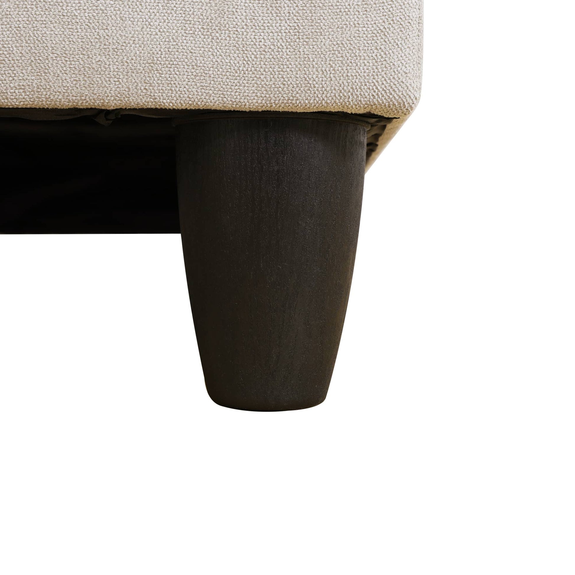 Tapered black sofa leg with textured beige upholstery detail