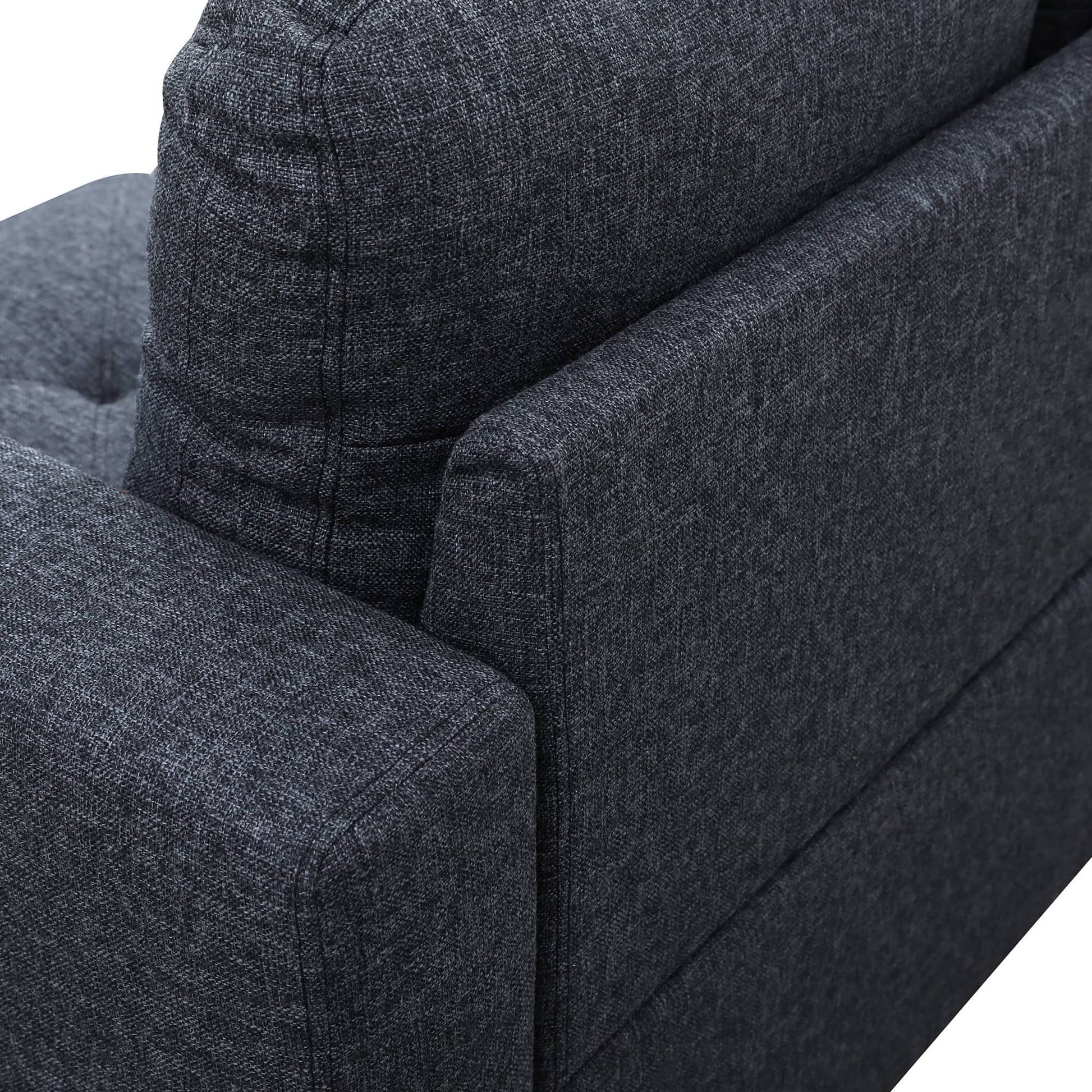 Closeup of dark charcoal textured fabric sofa armrest and back cushion