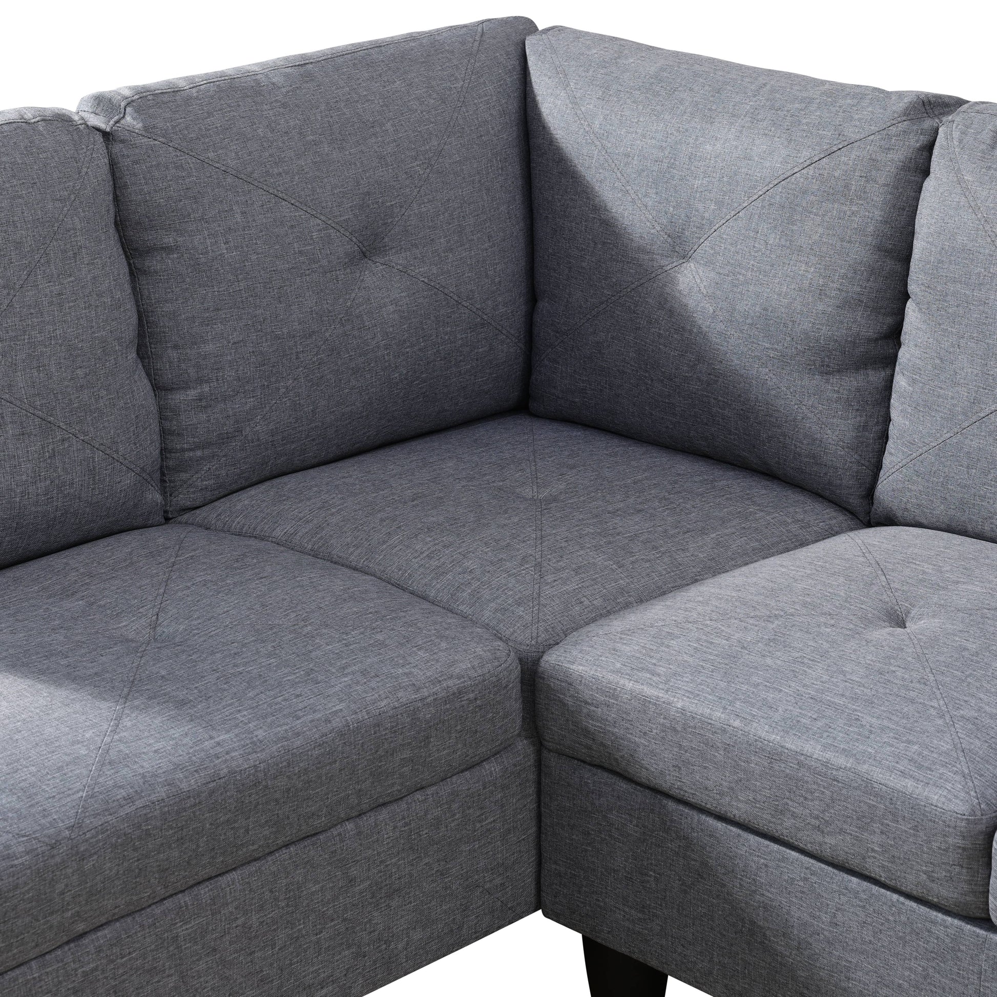 Closeup of a grey fabric sectional sofa corner with diamond tufting on back cushions
