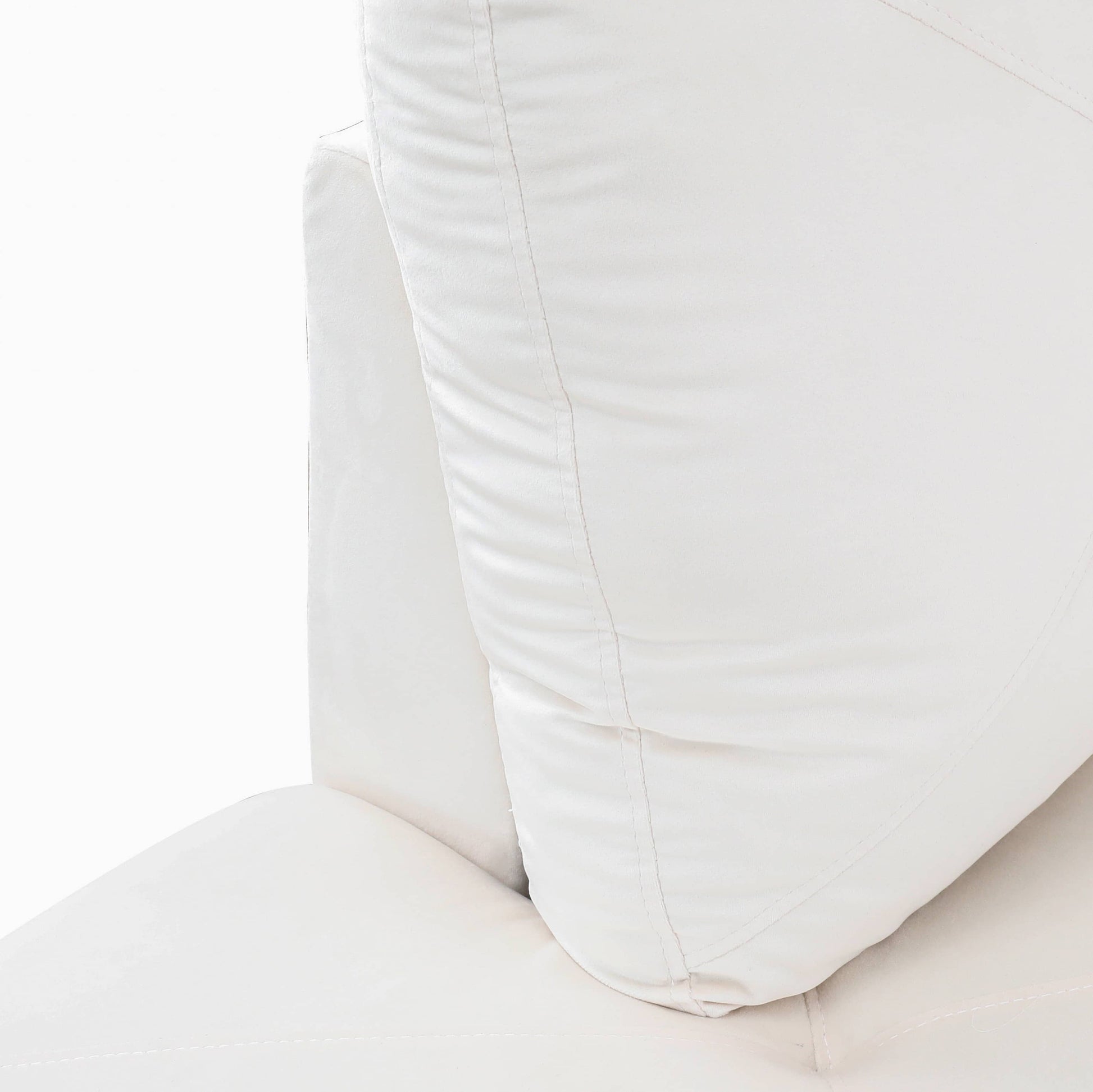 Closeup of plush white faux leather sofa cushion with visible stitching