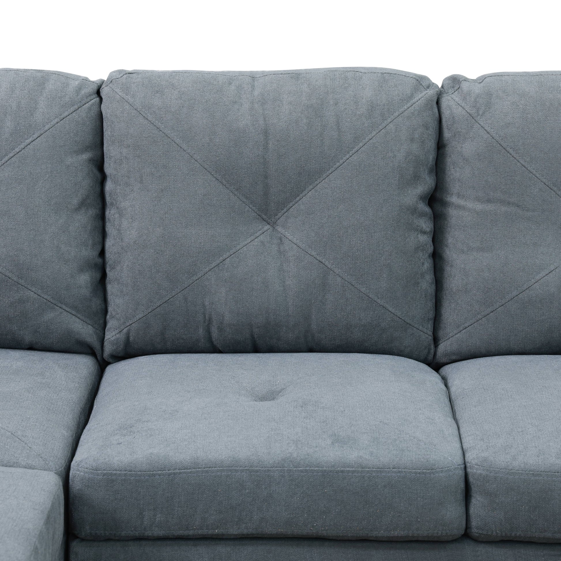 Close up of a charcoal grey sectional sofas upholstered seat cushions and tufted back pillows