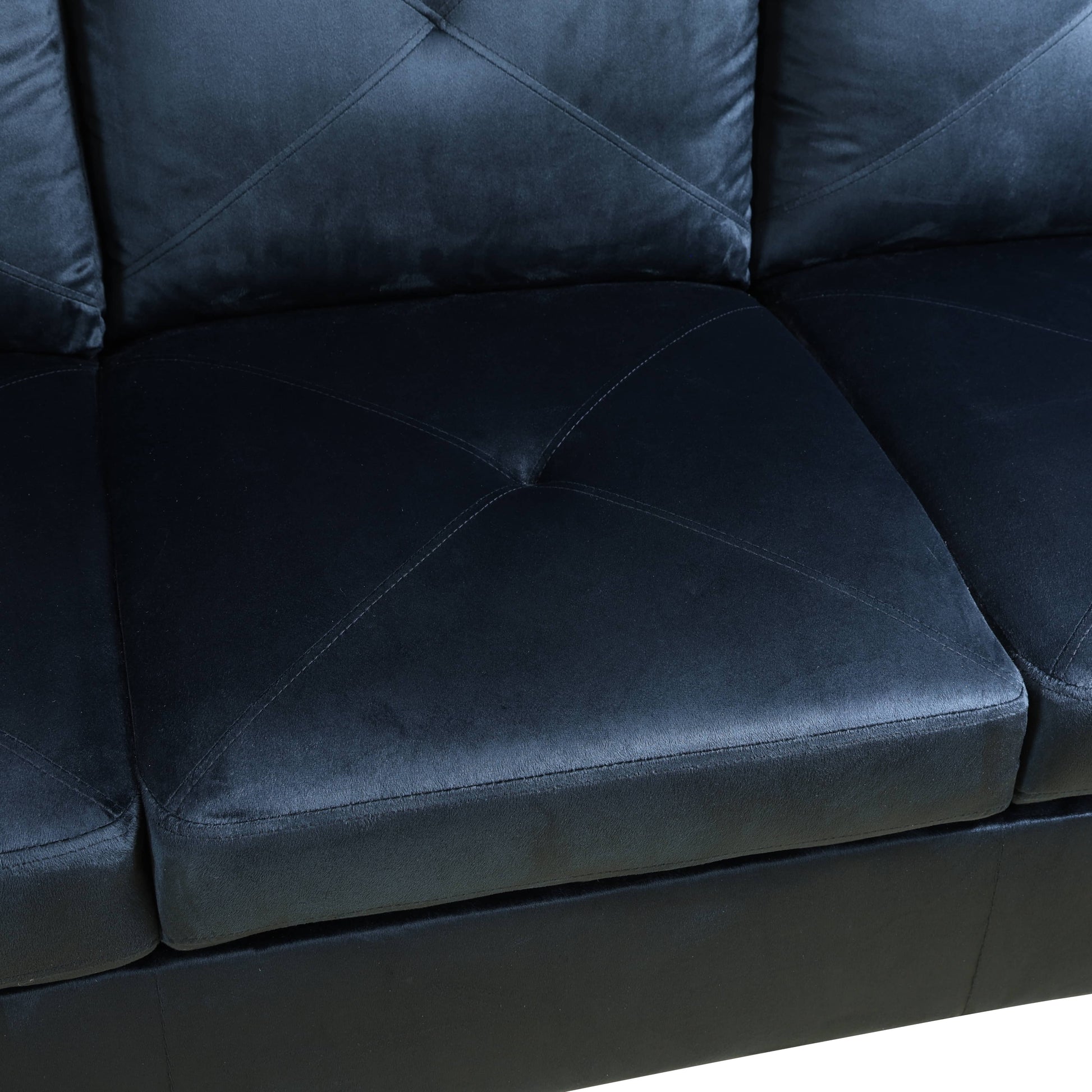 Black tufted faux leather sofa section with diamond stitching on seat cushions