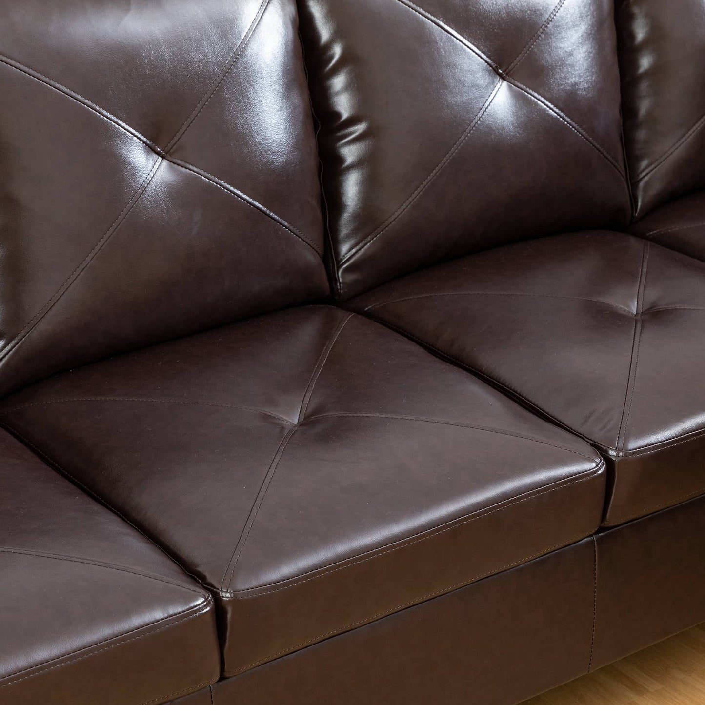 Detailed view of dark brown faux leather sofa cushions with diamond tufting and stitched seams