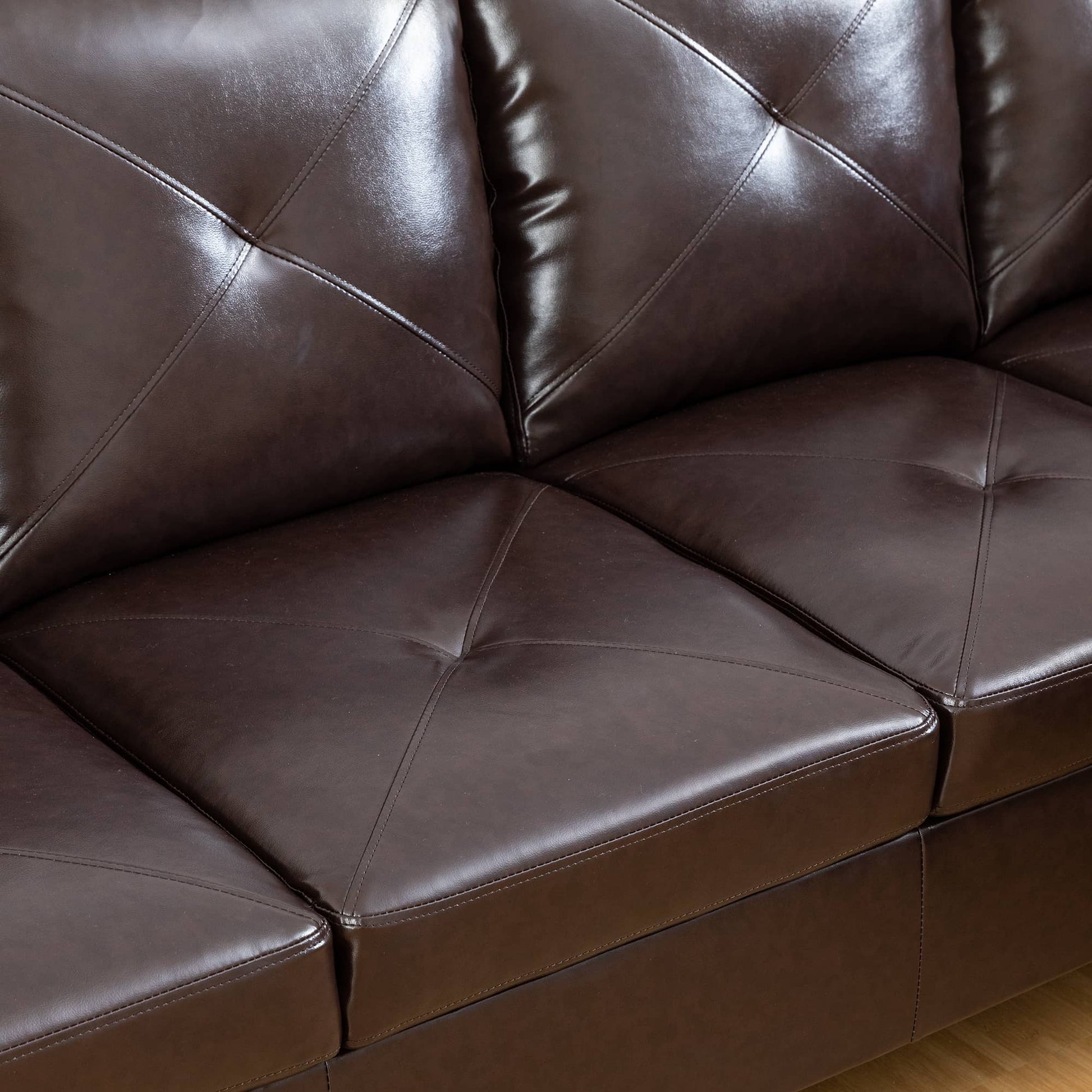 Detailed view of dark brown faux leather sofa cushions with diamond tufting and stitched seams