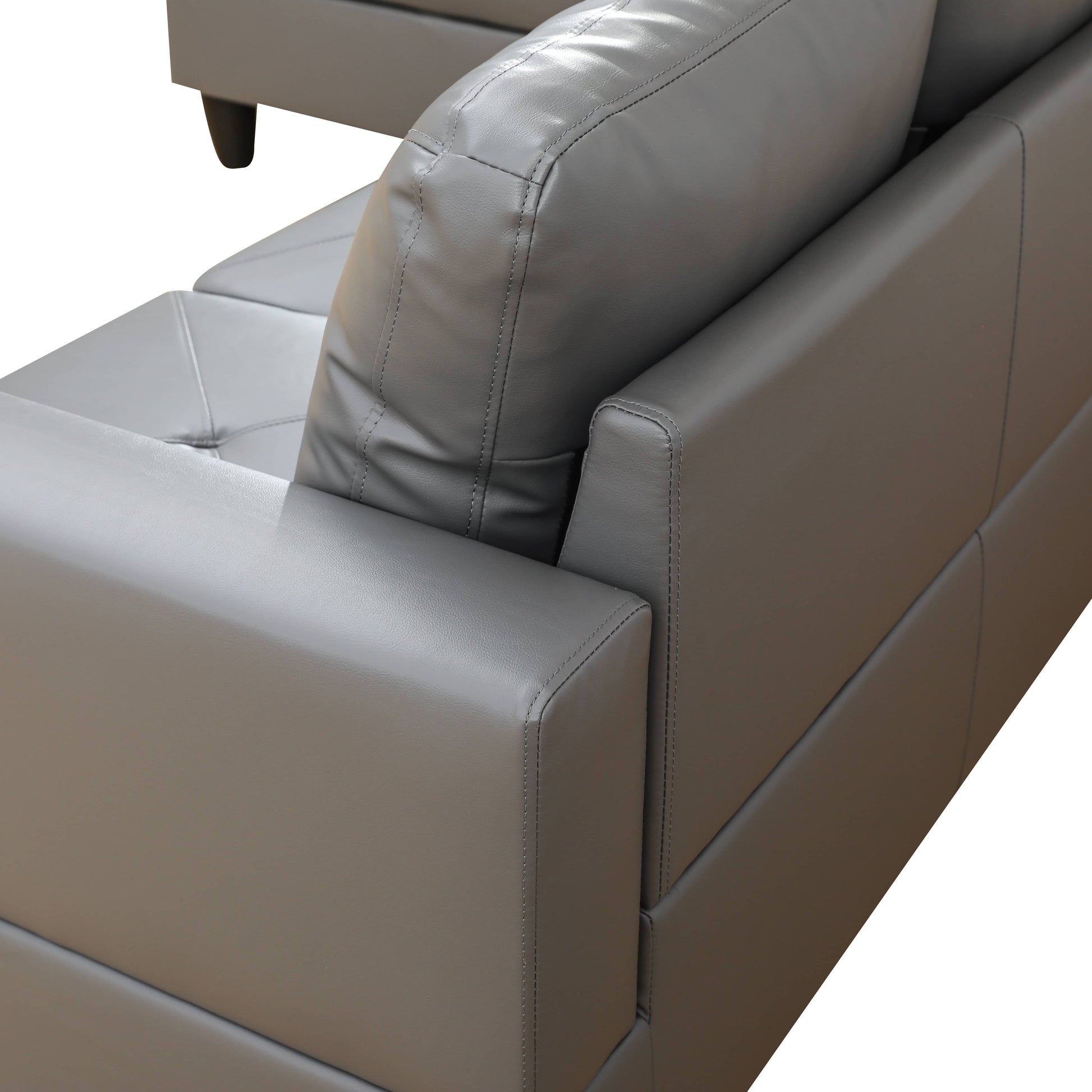 Closeup of a plush grey leather couch armrest with detailed stitching