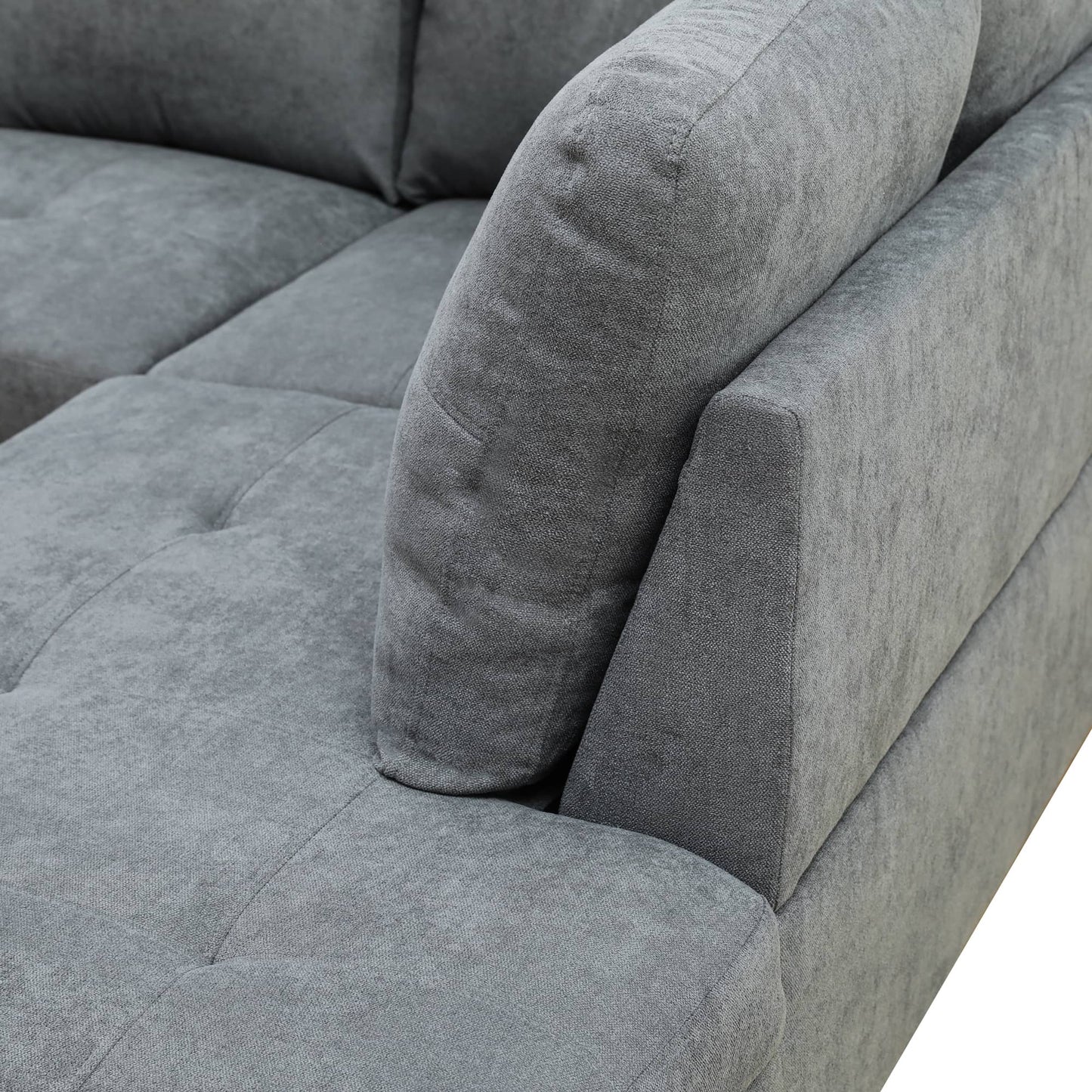 Closeup of a tufted grey fabric sectional sofa armrest