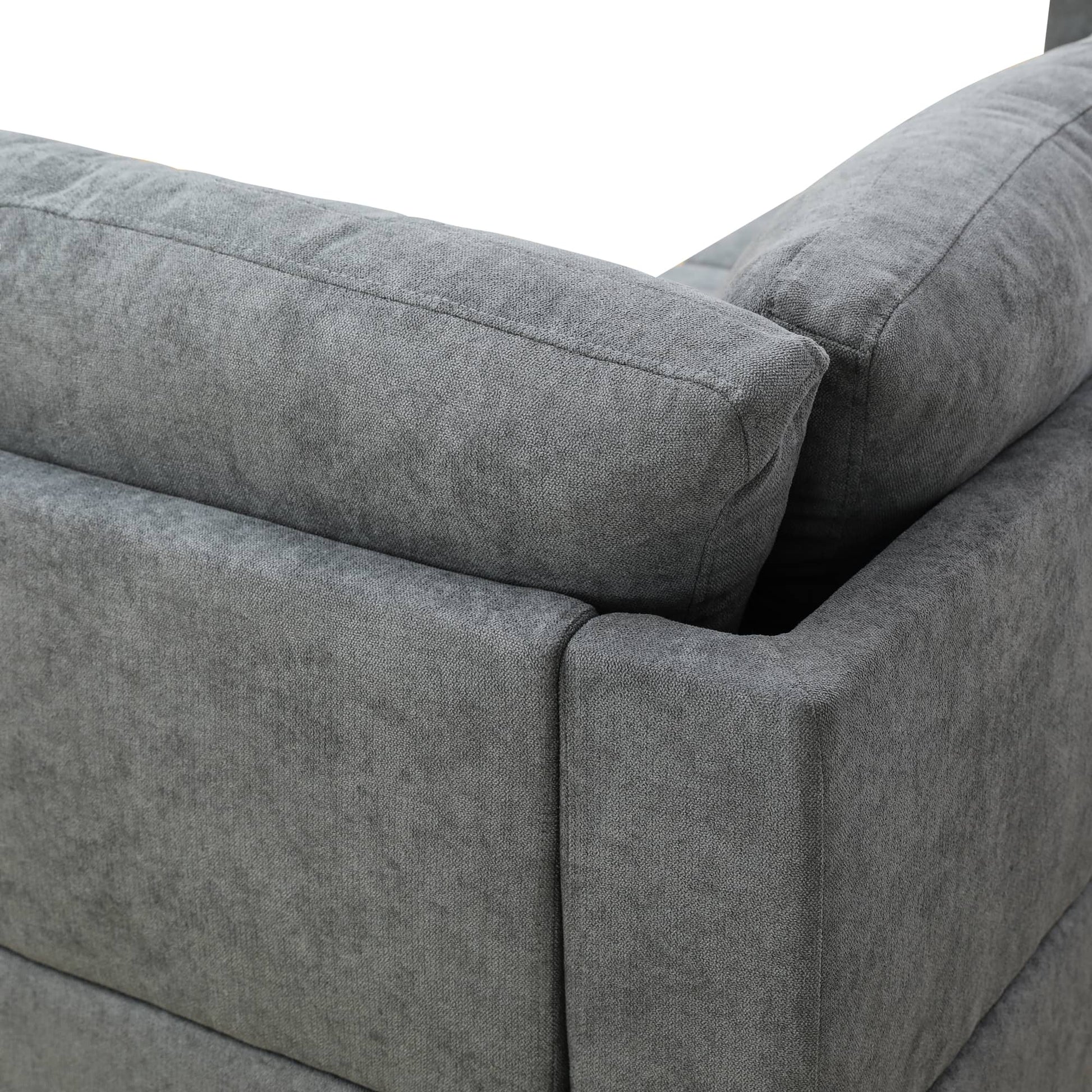 Closeup of a grey fabric sectional sofa armrest with stitched details
