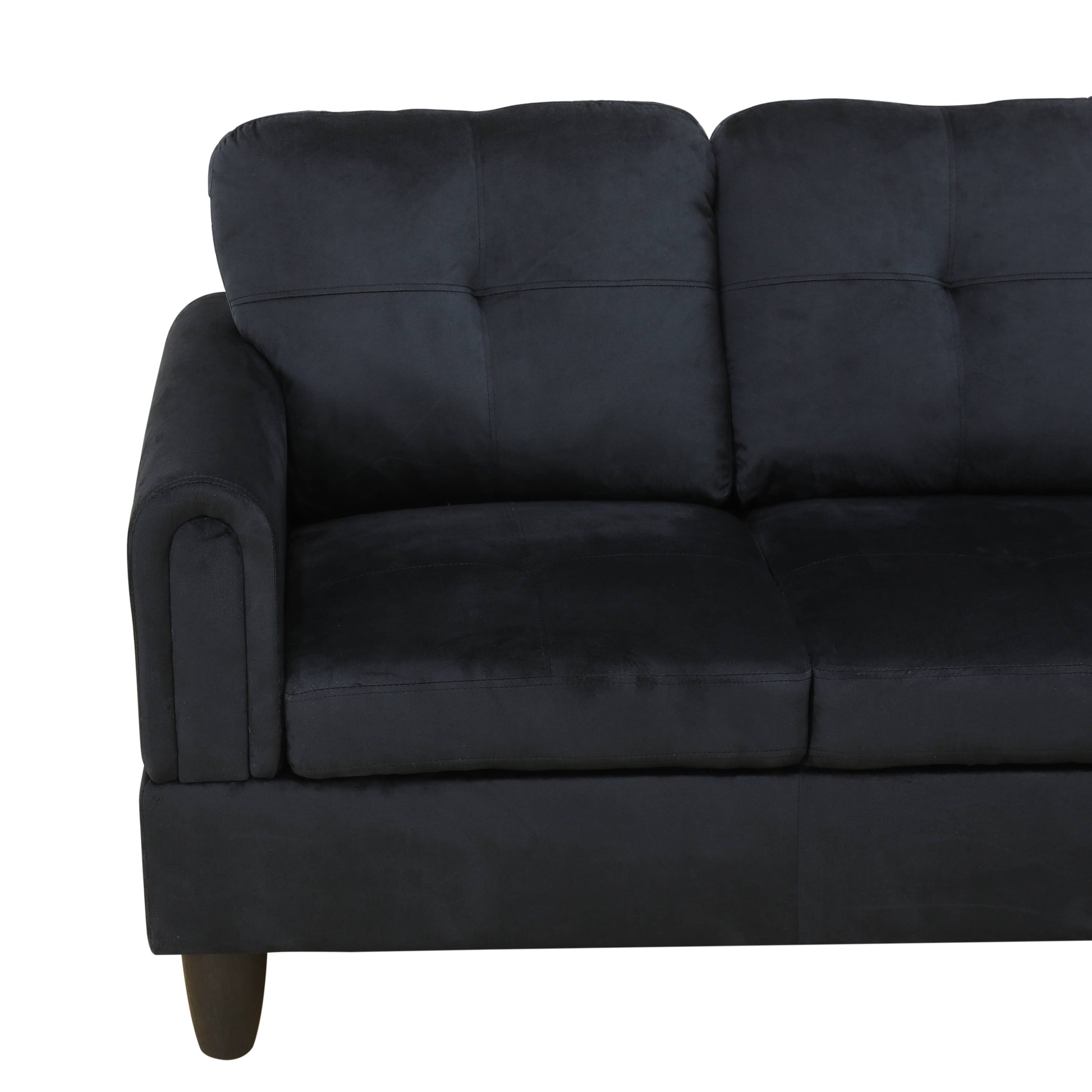 Black velvet sofa with tufted cushions and a rounded armrest