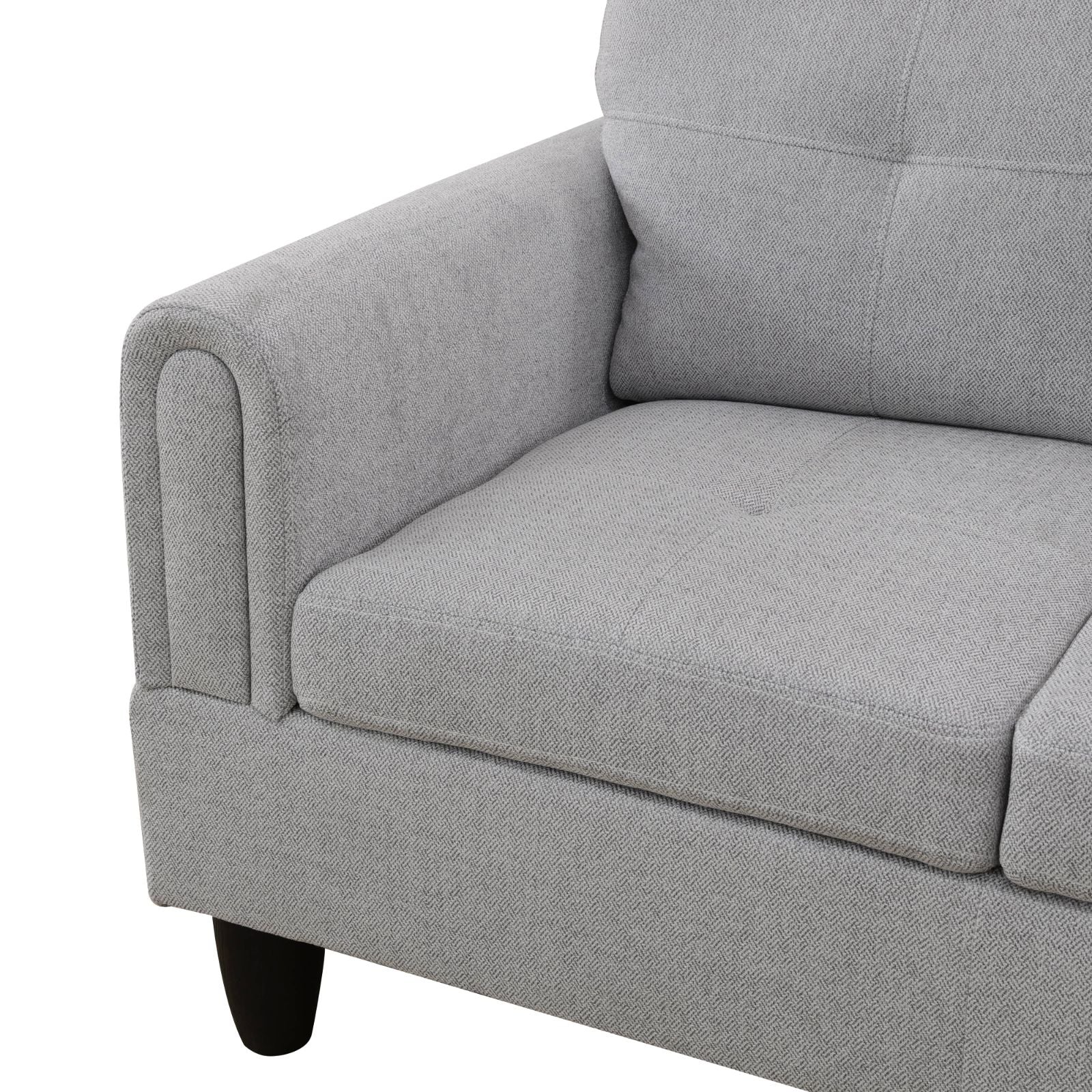 Closeup of a modern grey fabric sofa armrest with tufted details