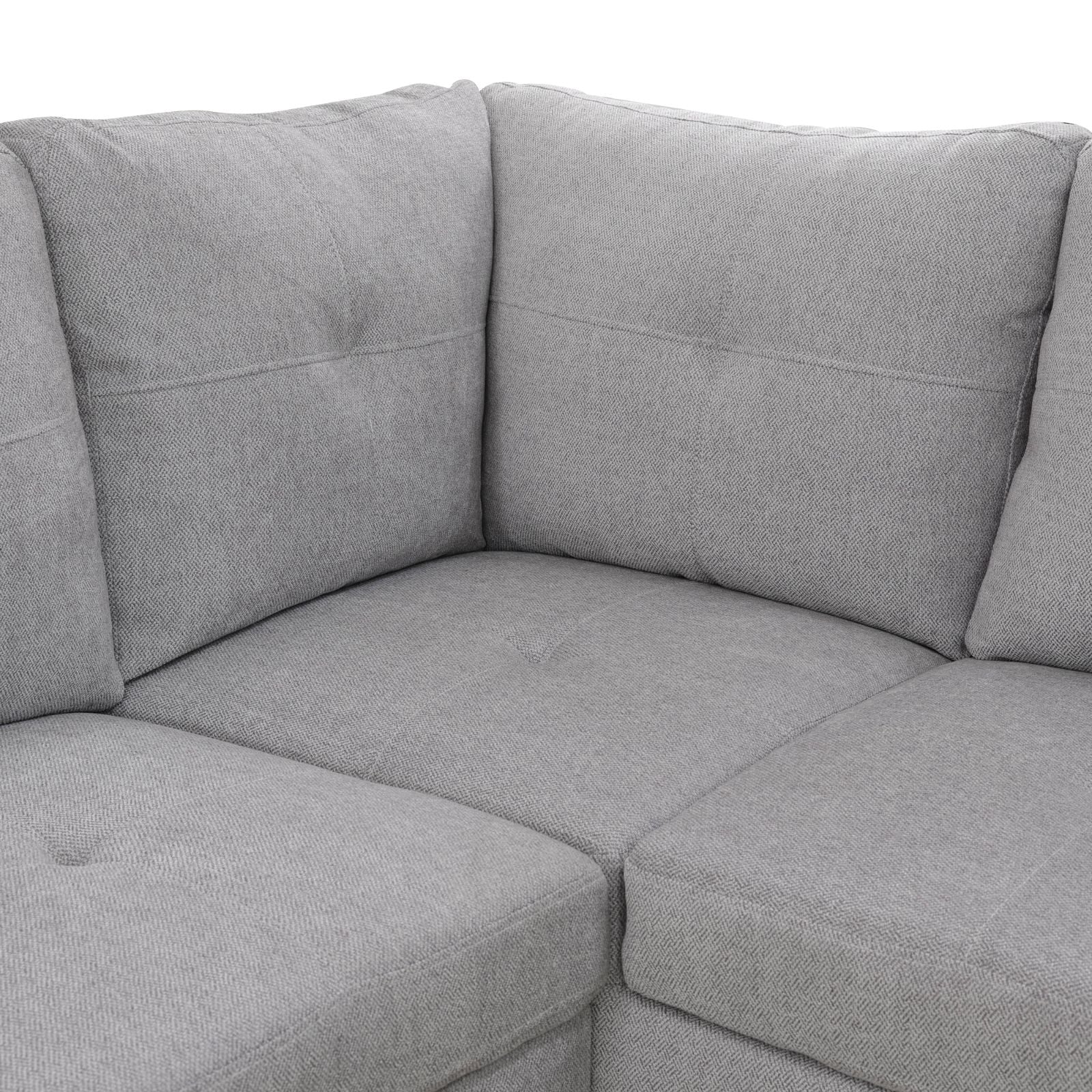 Closeup of a gray fabric sectional sofa with plush cushions and stitched detailing
